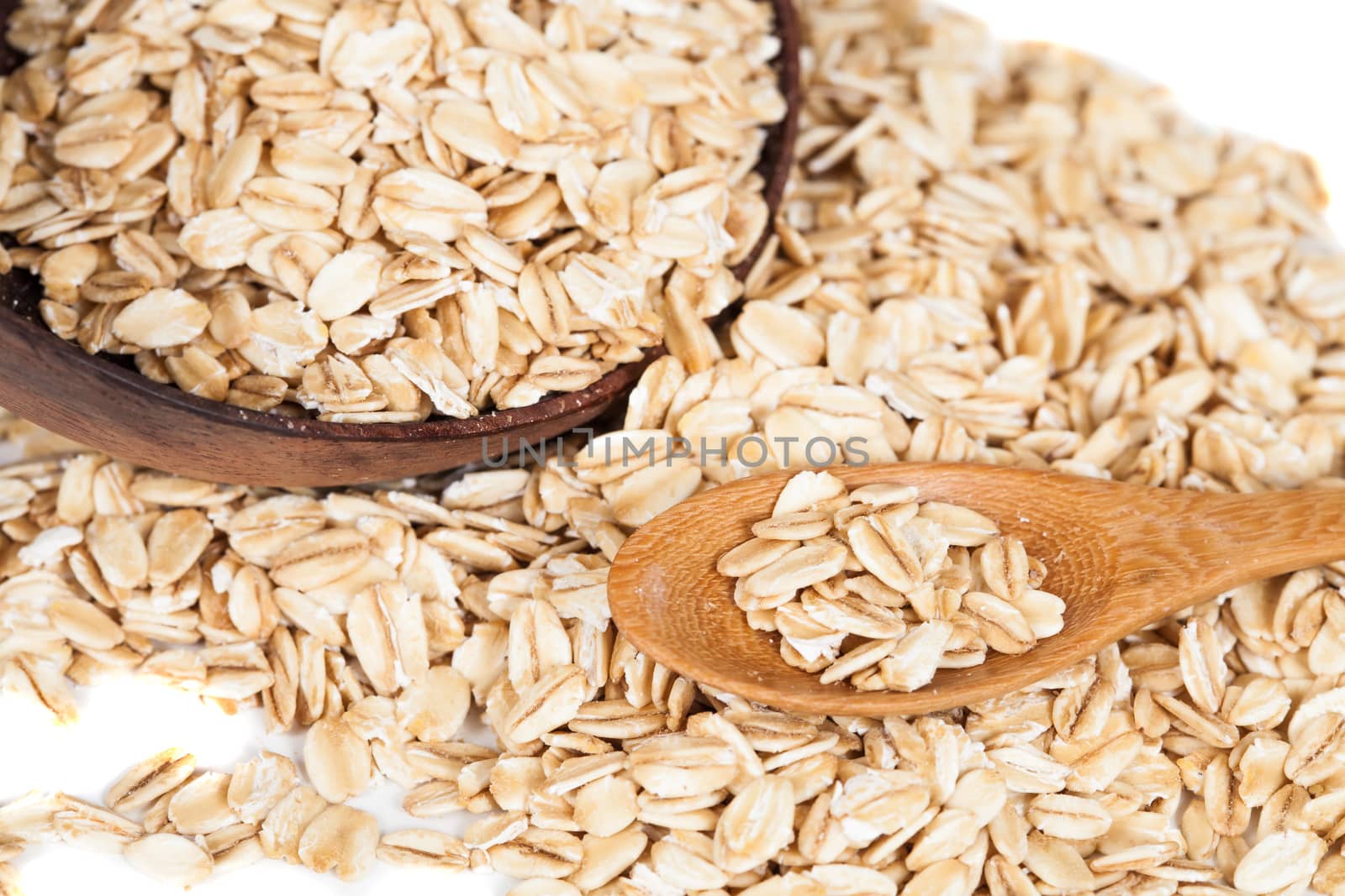 Oats flakes pile in wood spoon on white background