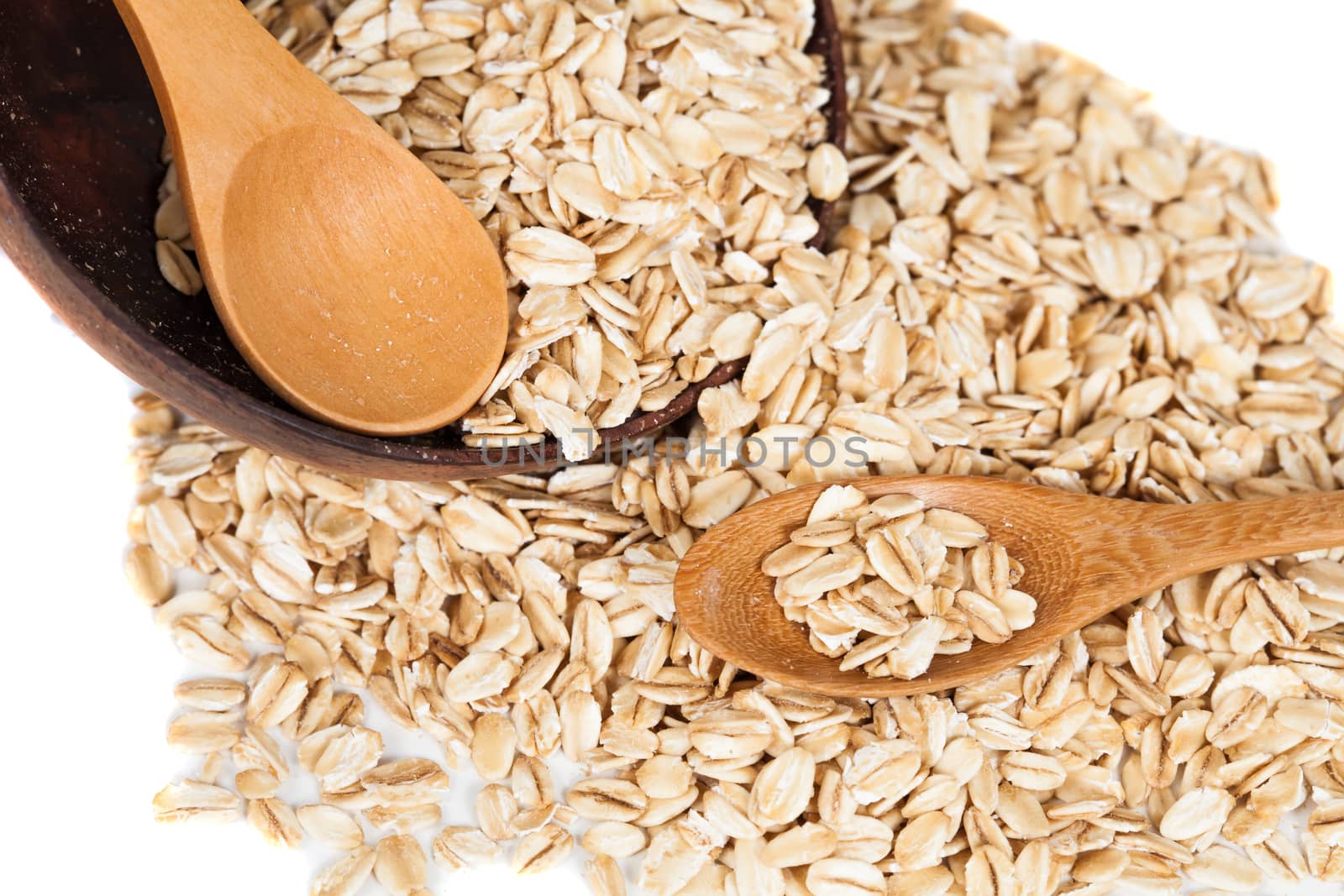 Oats flakes pile in wood spoon on white background