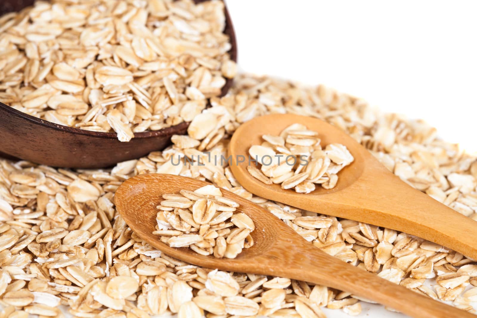 Oats flakes pile in wood spoon on white background