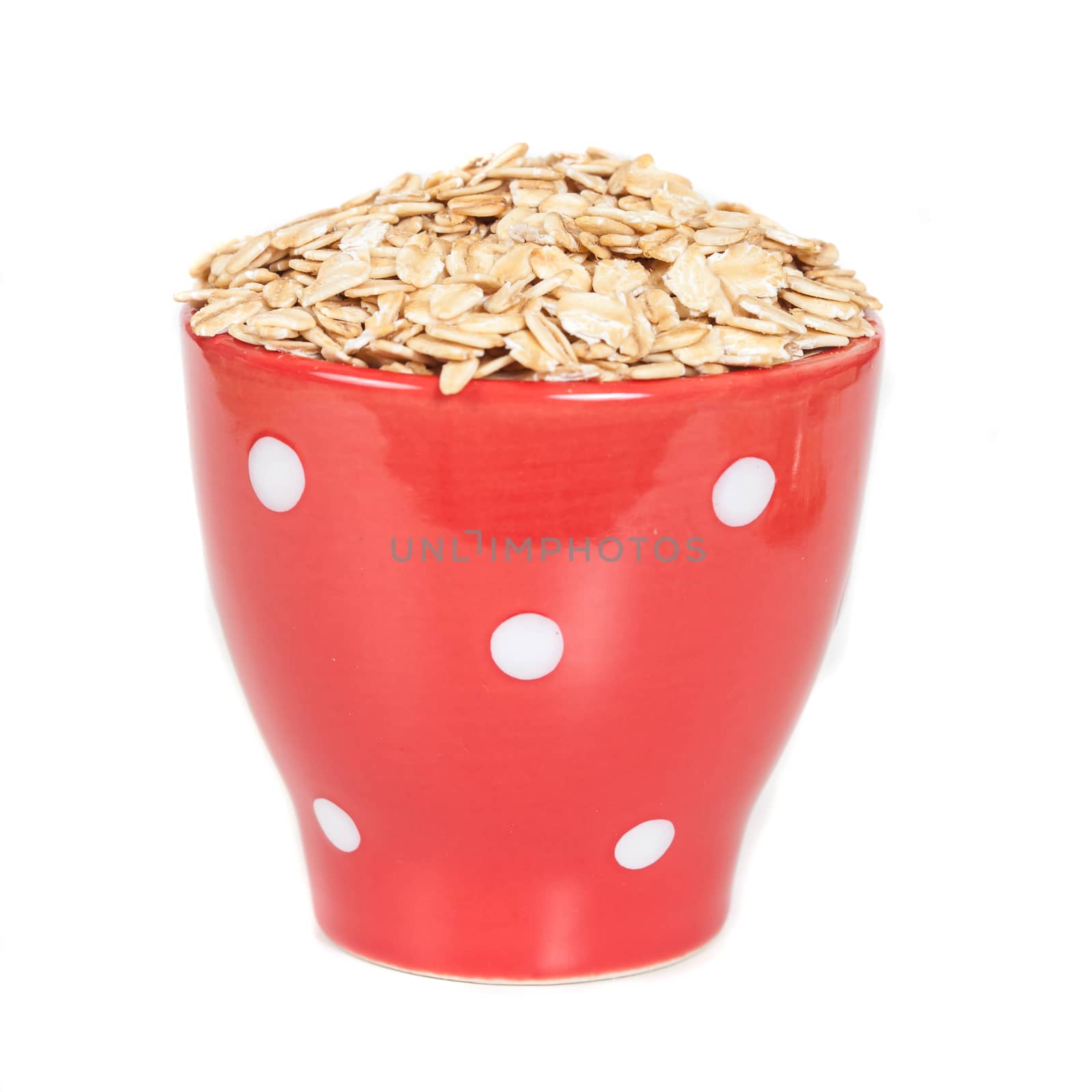 red cup with oats flakes pile on white background.