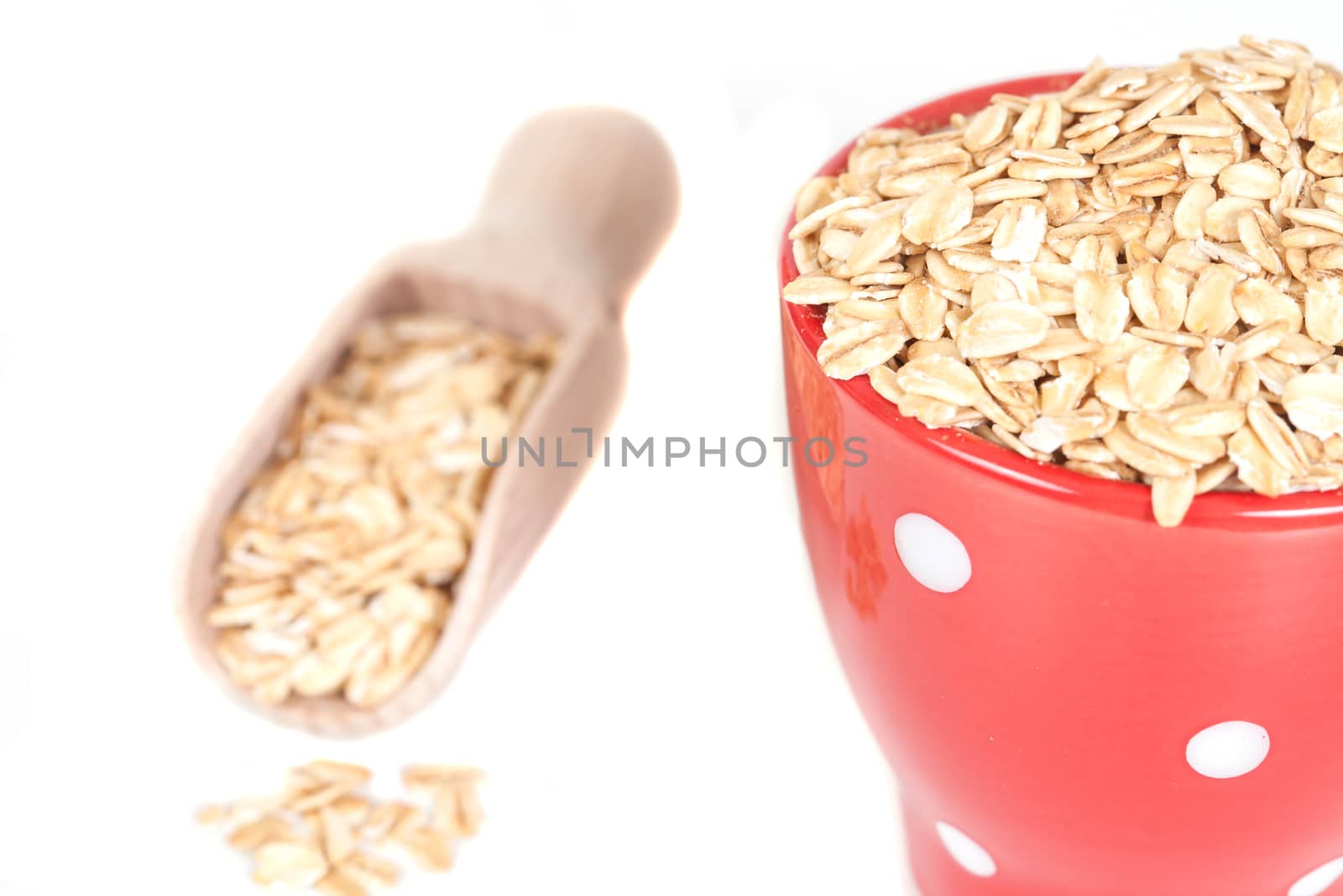 red cup with oats flakes pile on white background. by amnarj2006