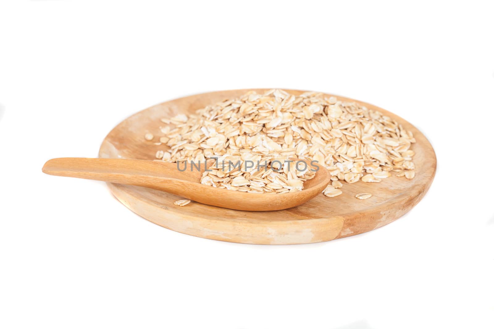 dish and wood spoon with oats flakes pile