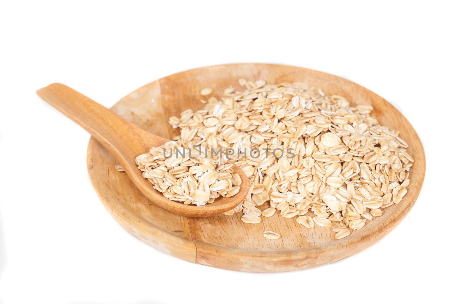 dish and wood spoon with oats flakes pile