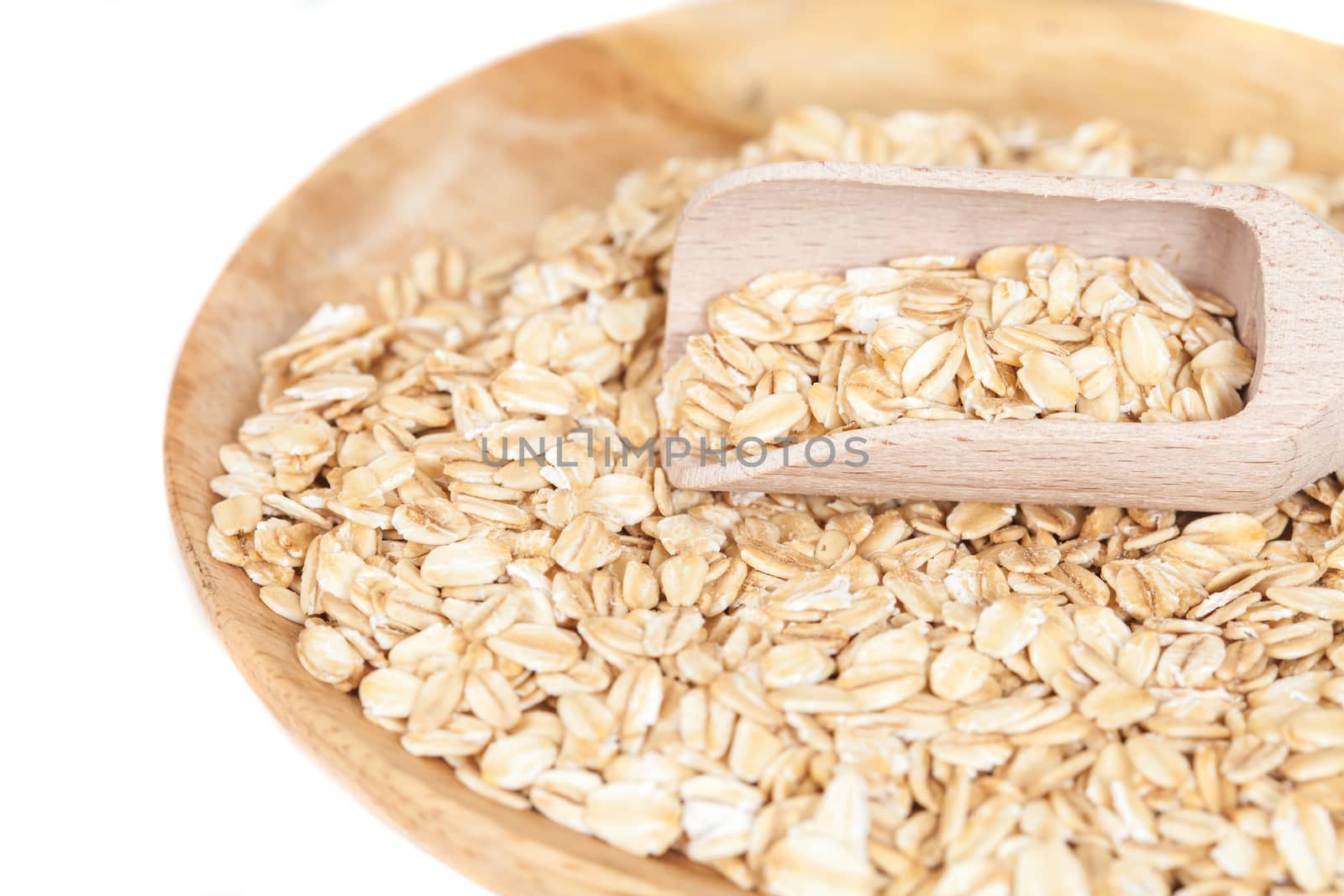 dish and wood spoon with oats flakes pile