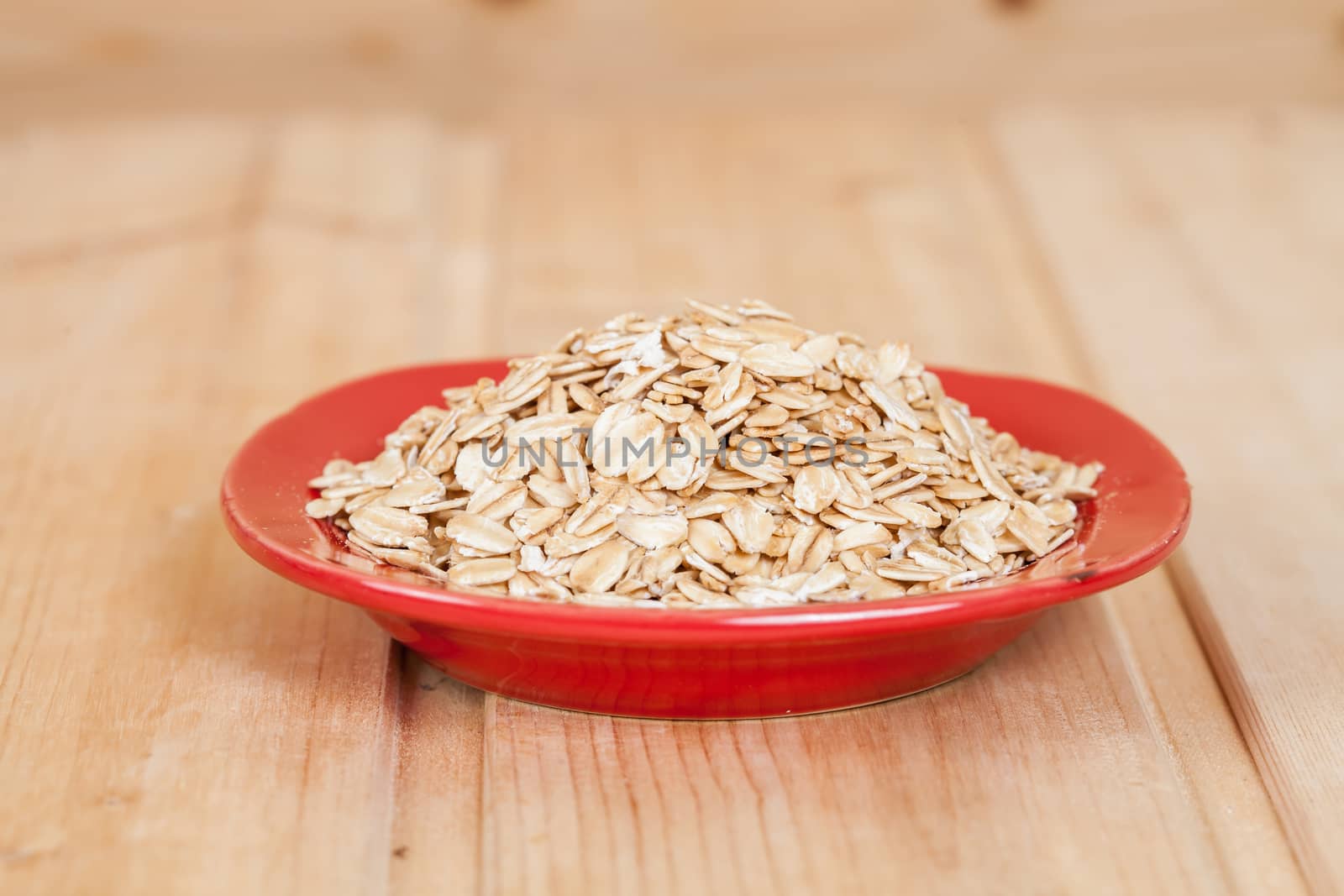 red dish  with oats flakes pile on wood background.