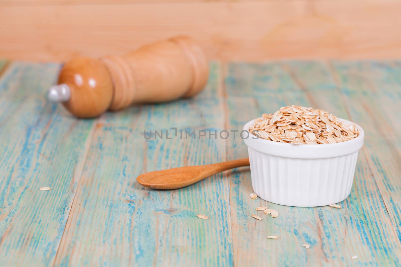 oats flakes pile in bowl on wood background.