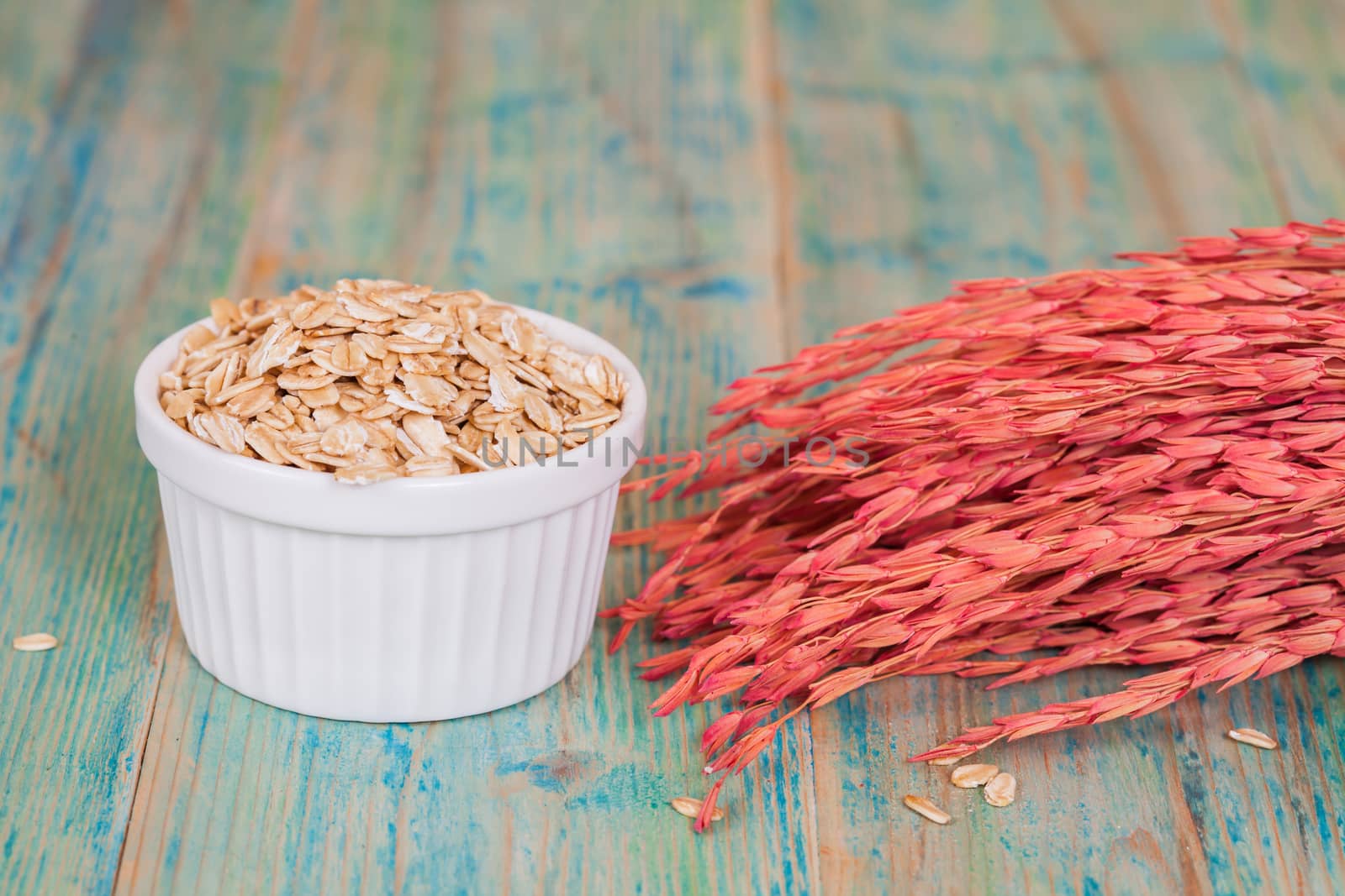 oats flakes pile in bowl on wood background.