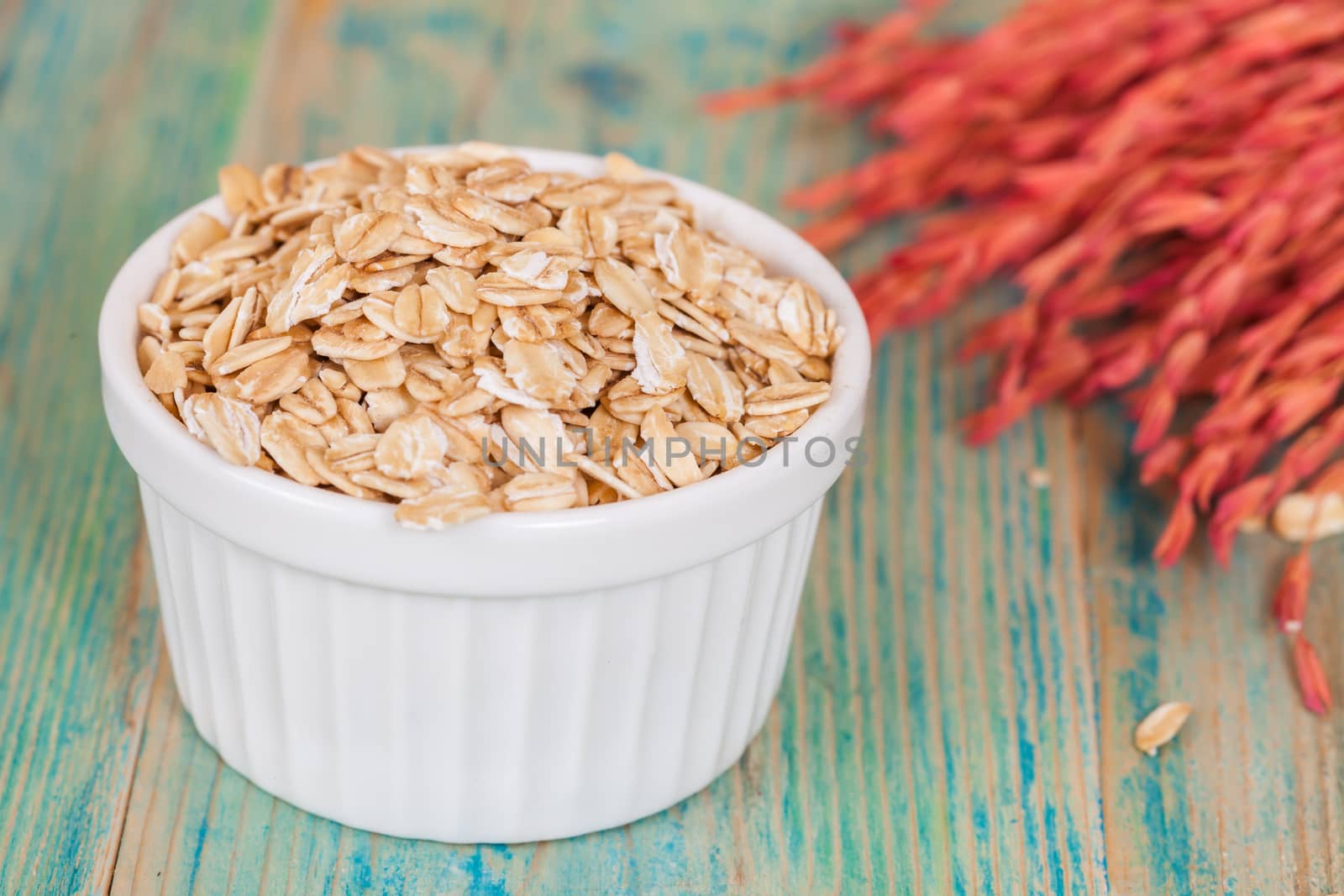 oats flakes pile in bowl on wood background.