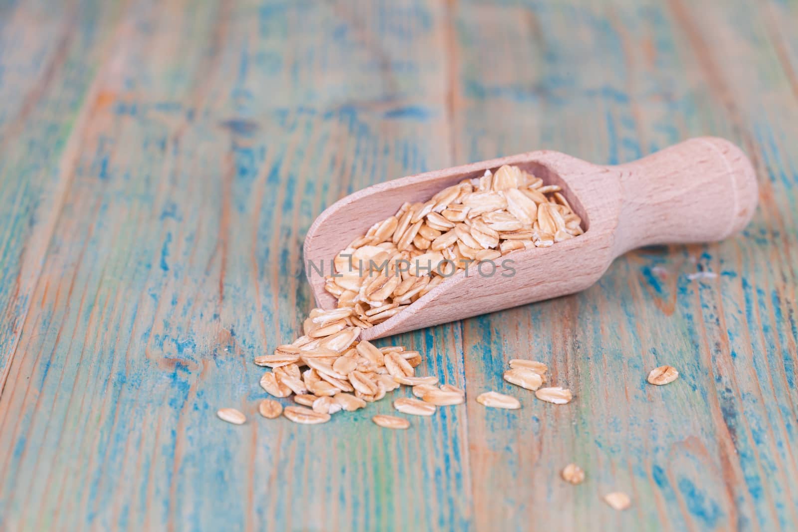 wood spoon with oats flakes pile on wood 
background.