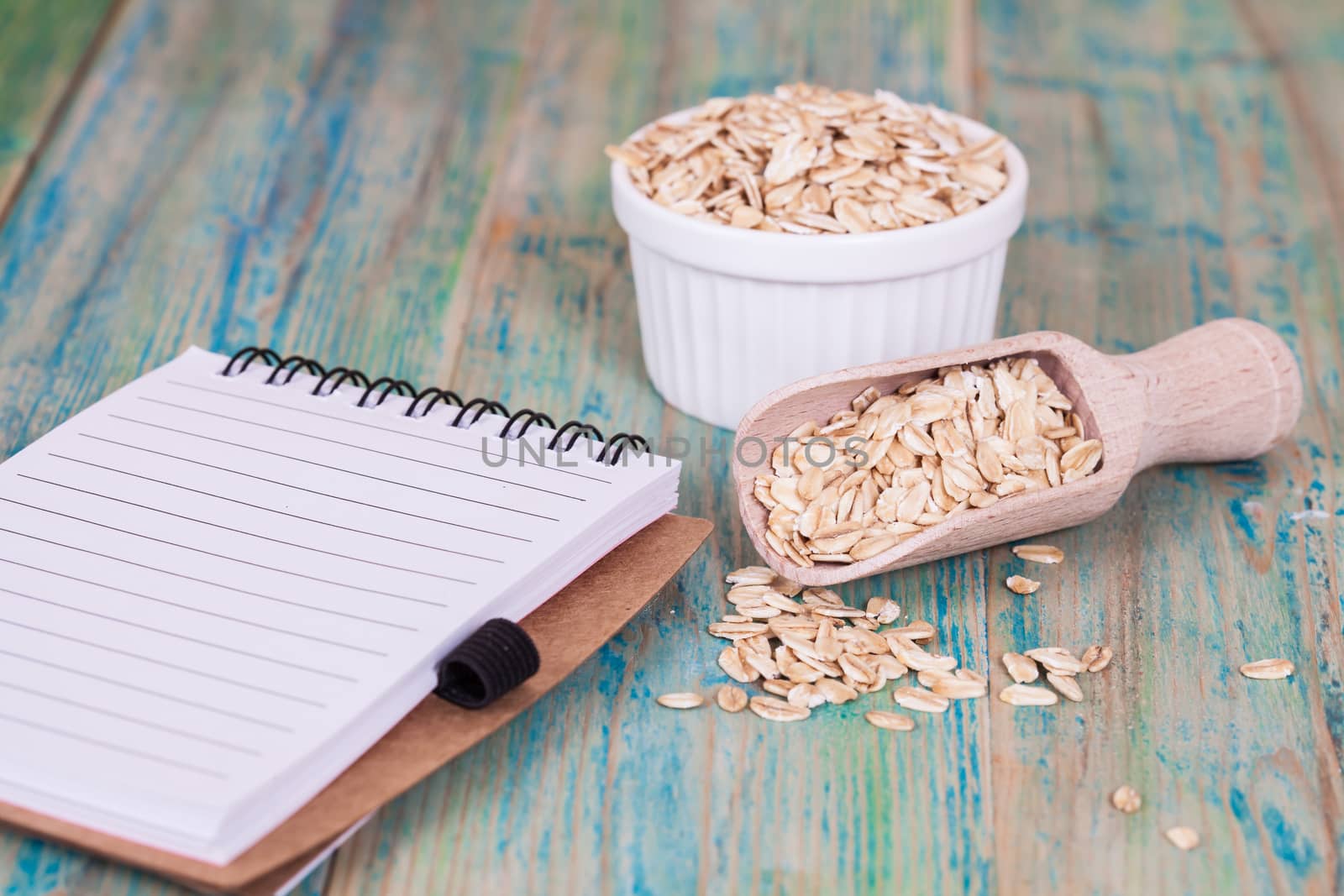 wood spoon with oats flakes pile and book note