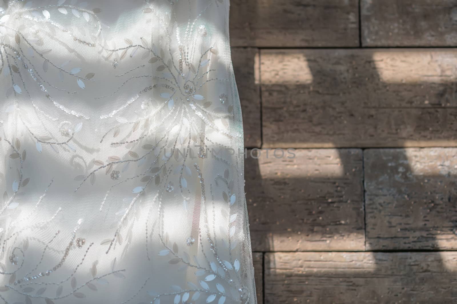 Wedding dress close up hanging on brown granite background, painted with light and shadow.