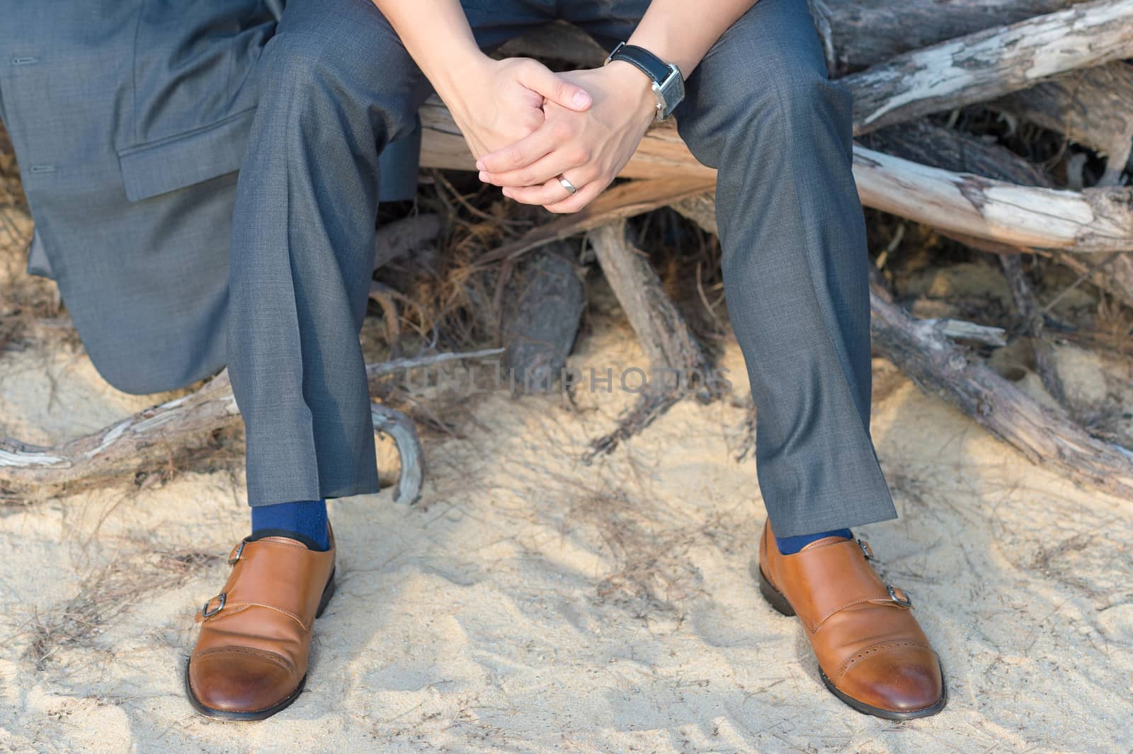 A man sitting on roots staring out to the sea.