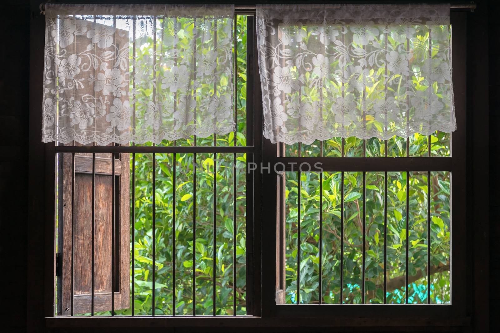 Old style Thai window with top-half lace curtain.