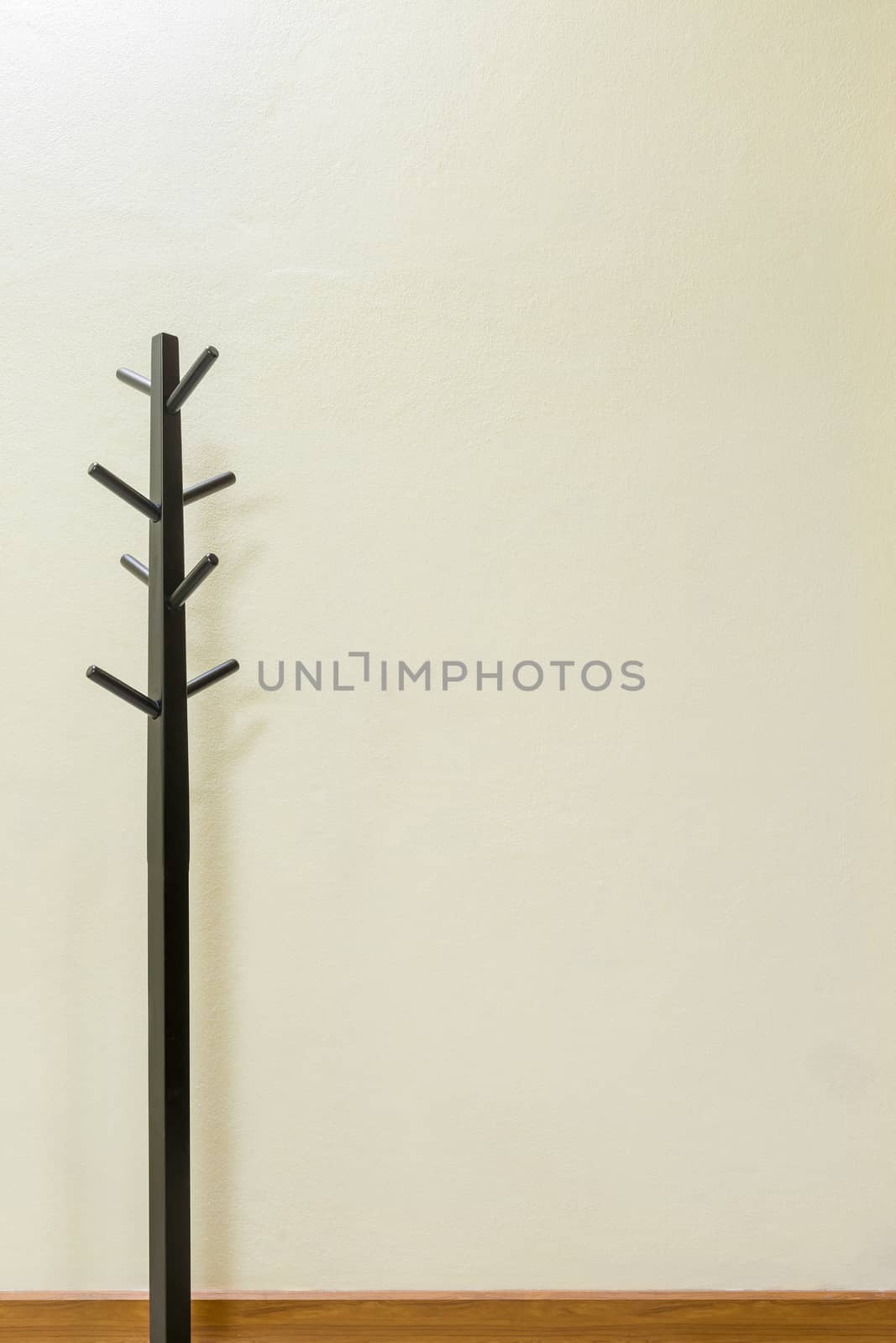 Black wooden coat rack on wall background, space for input text.