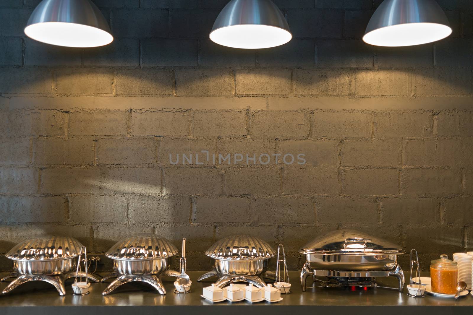 Buffet line food containers shaped shells, with three lighting and dark bricks wall background.