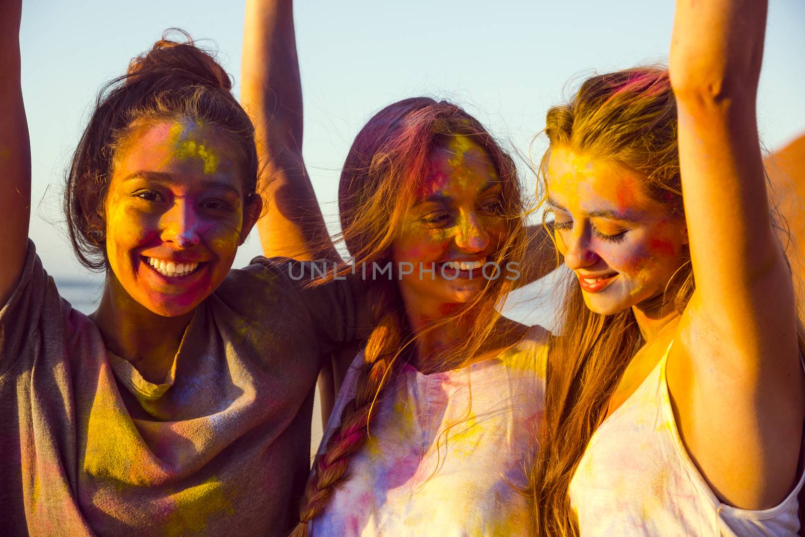 Teenagers playing with colored powder on the beach