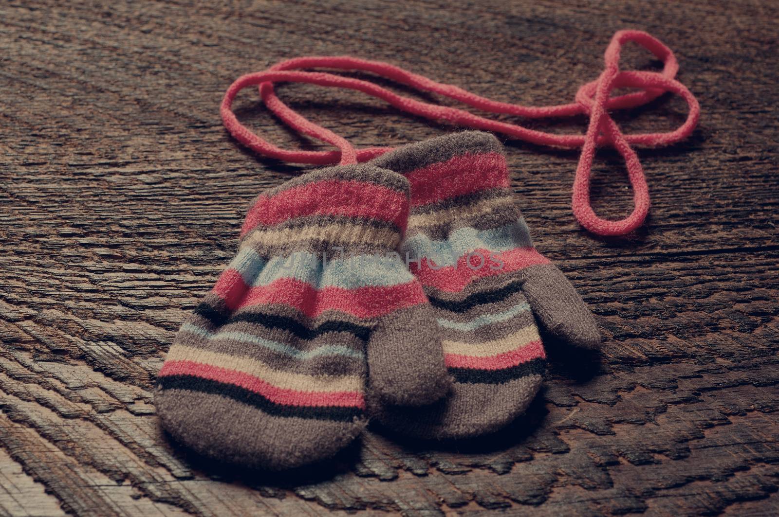 two knitted striped baby mittens on wood background