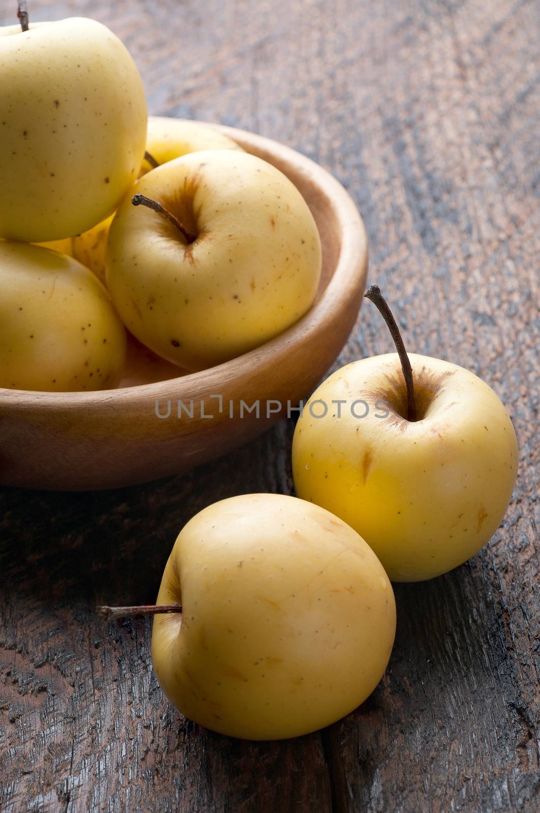 a few green apples in a wooden bowl on the table