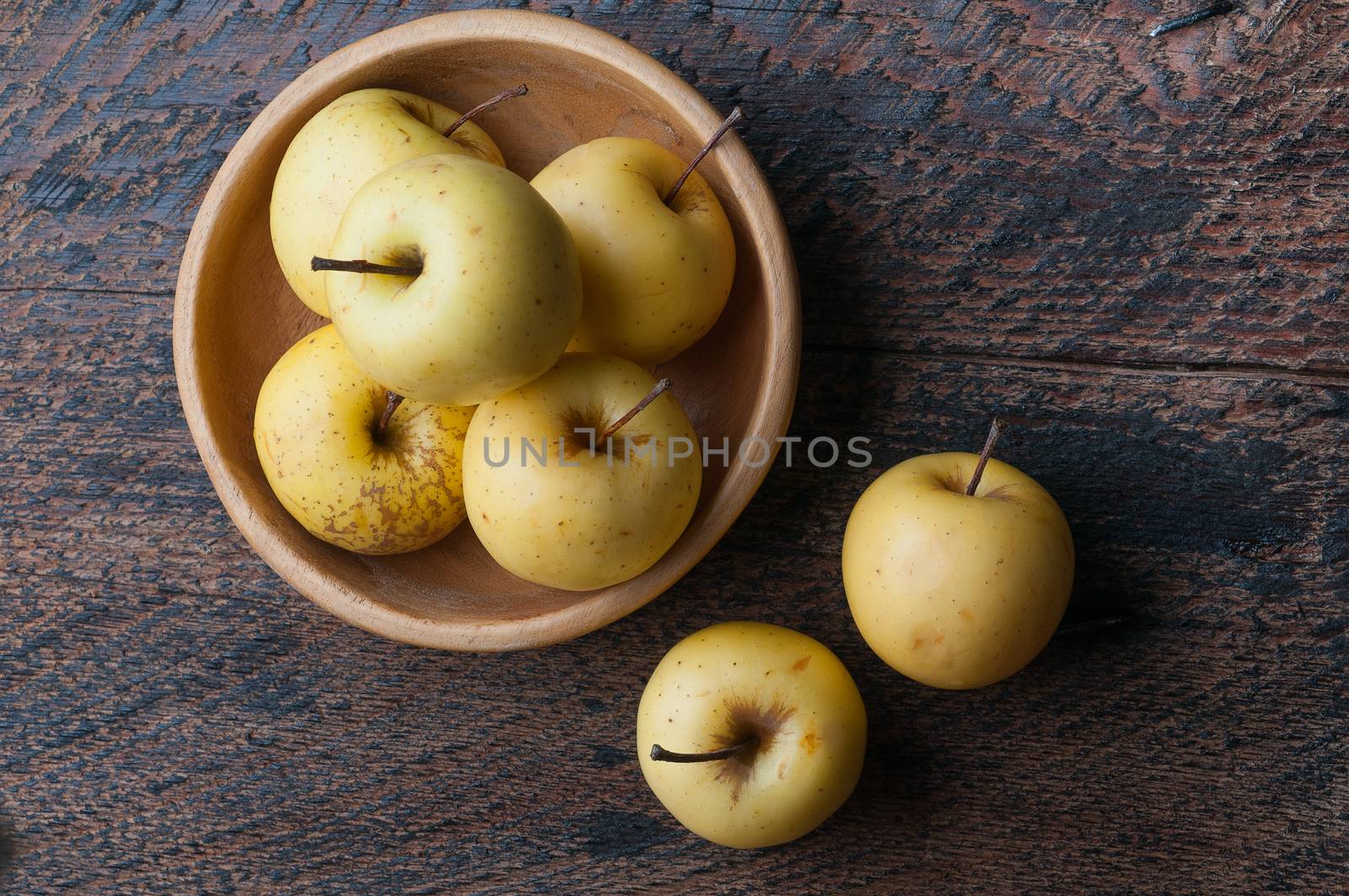 a few green apples in a wooden bowl on the table