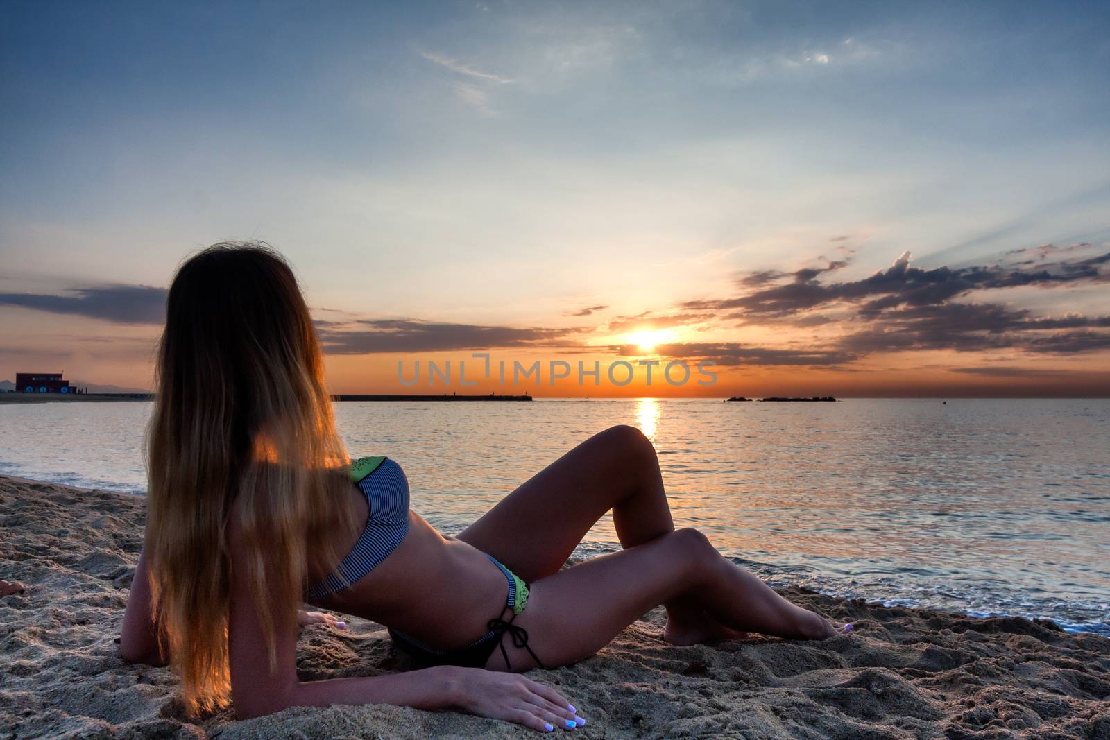 attractive sexy woman in bikini laying on sand on lonely beach by johnqsbf