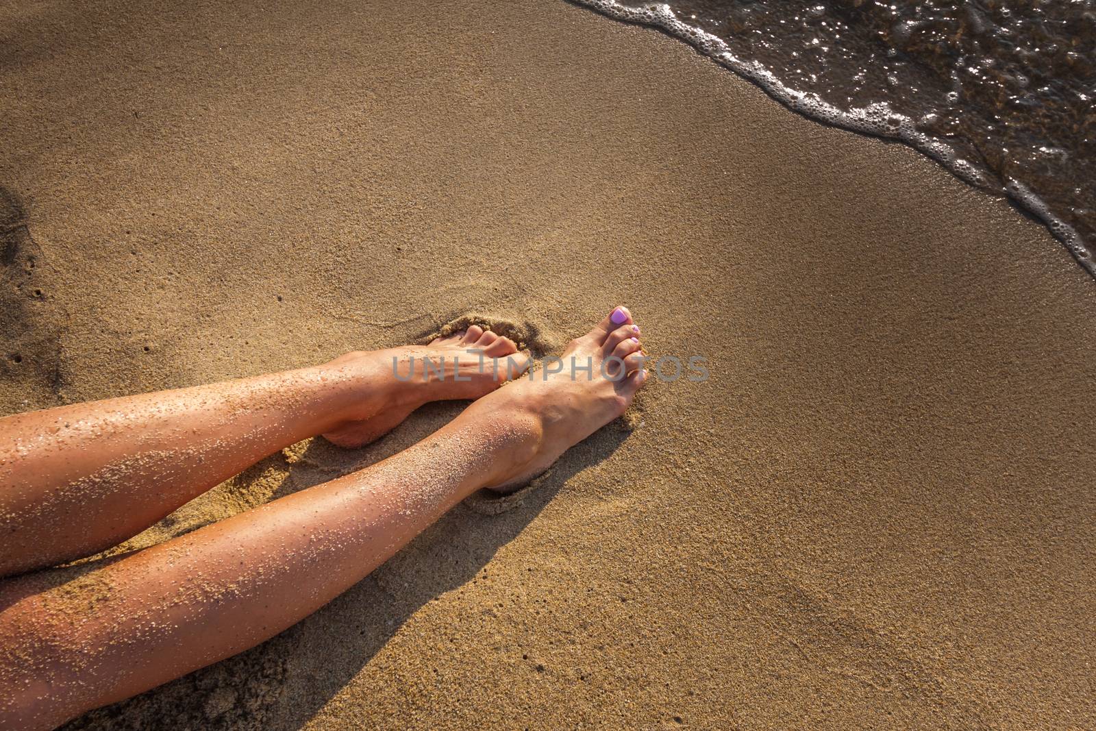 Women's sexy legs on the yellow sand beach