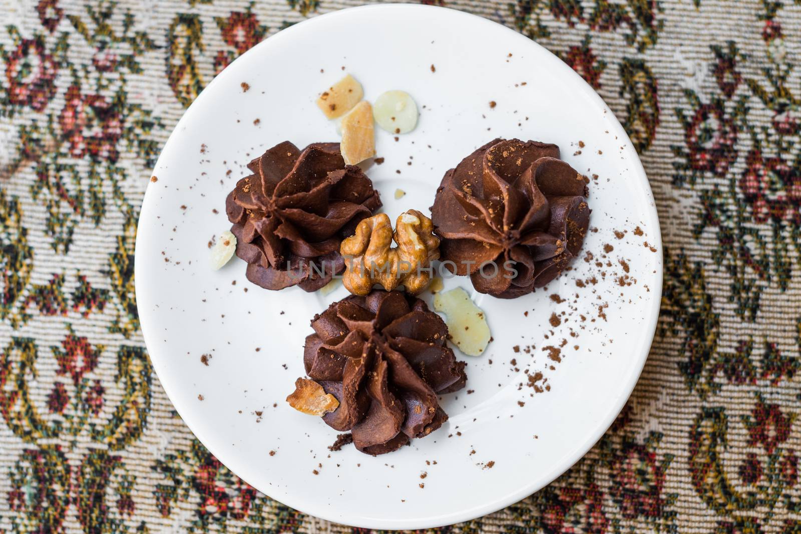 Homemade chocolate truffles with nuts and cocoa powder in a white plate