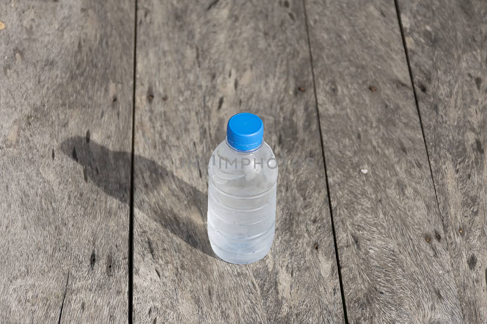 Plastic water bottle on wooden table texture. Fresh concept.