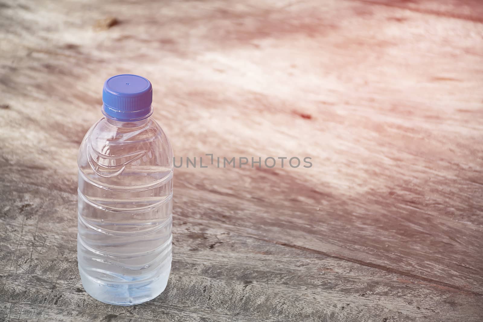 Plastic water bottle on wooden table texture. Fresh concept.