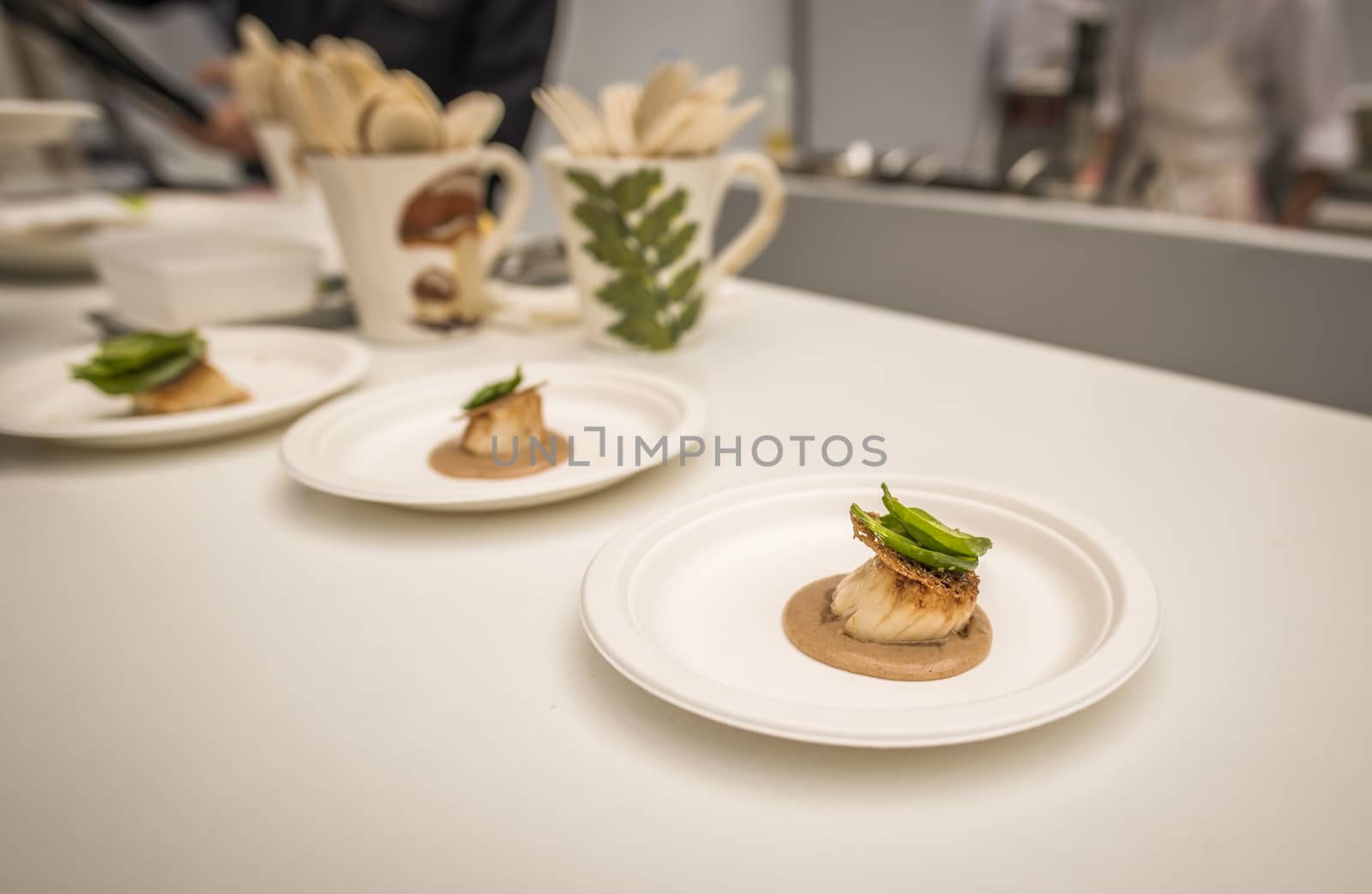 French kitchen with a small portion of salmon and dressing on a white table.