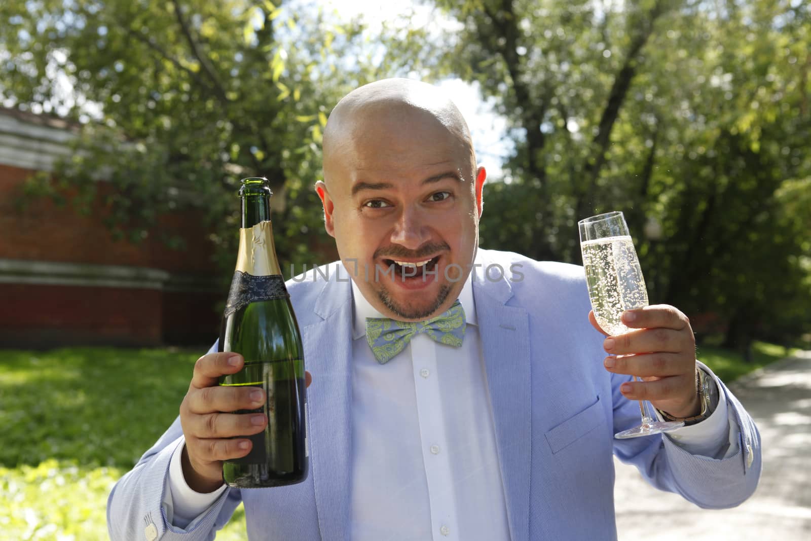 Happy groom with a bottle of champagne by friday