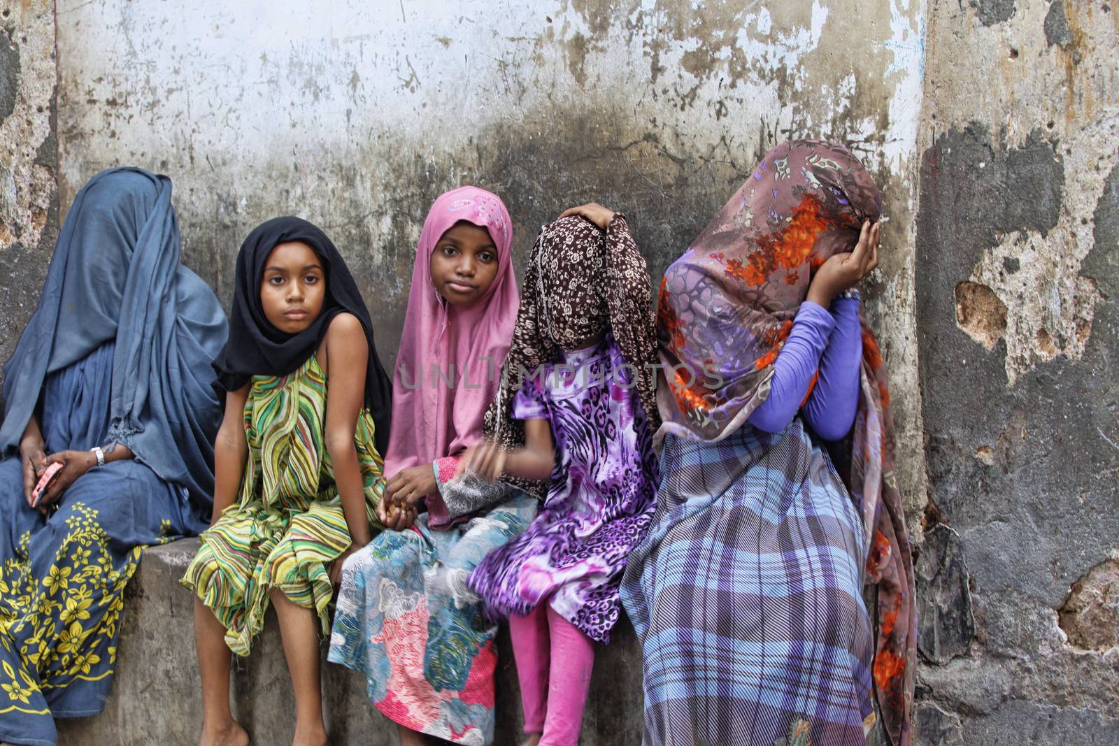 Stone Town, Tanzania - January 10, 2016: Children in traditional Muslim clothes sitting on the street of Stone Town.