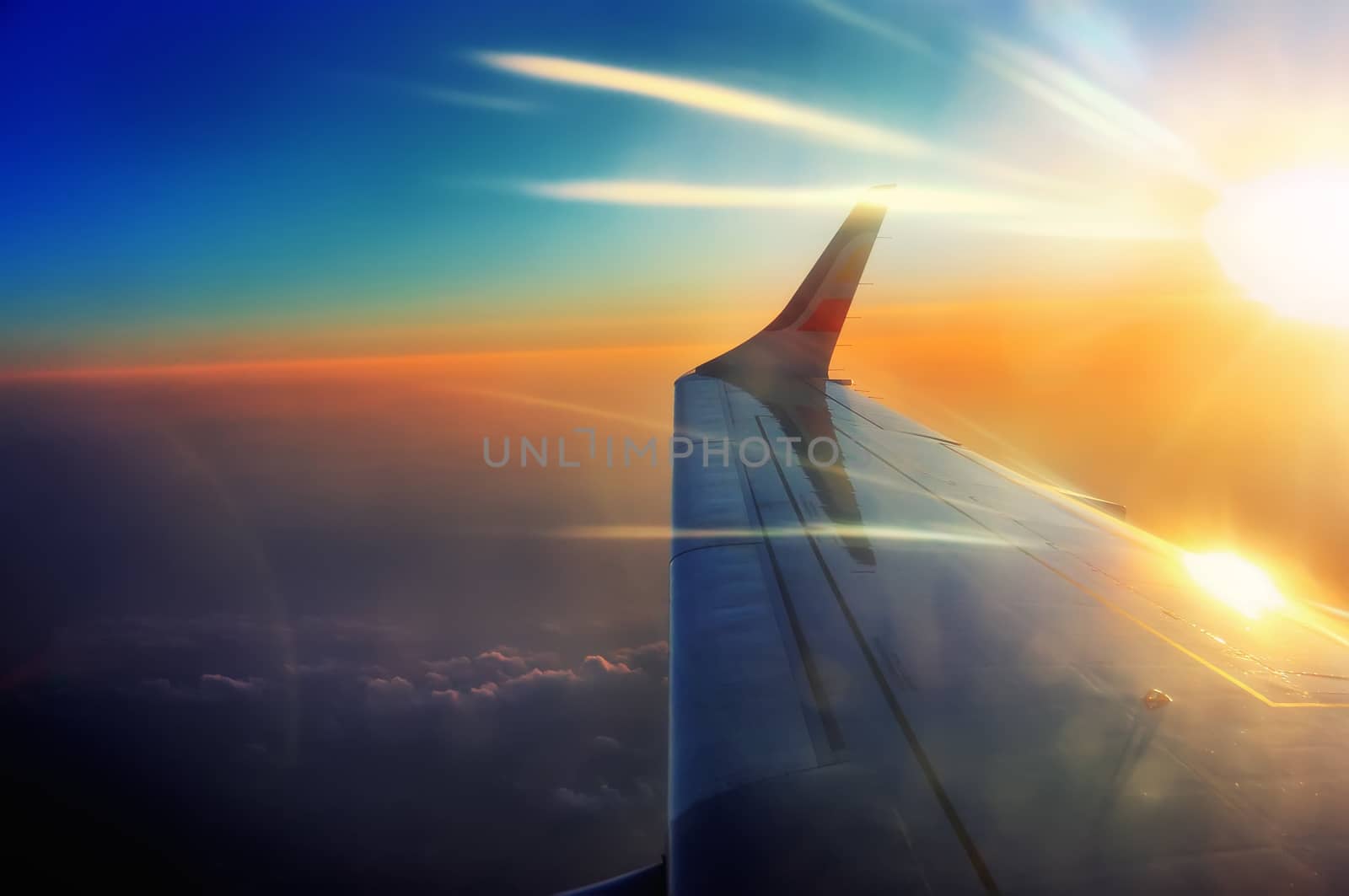 porthole view wing of the airplane in flight in sunrise beams 