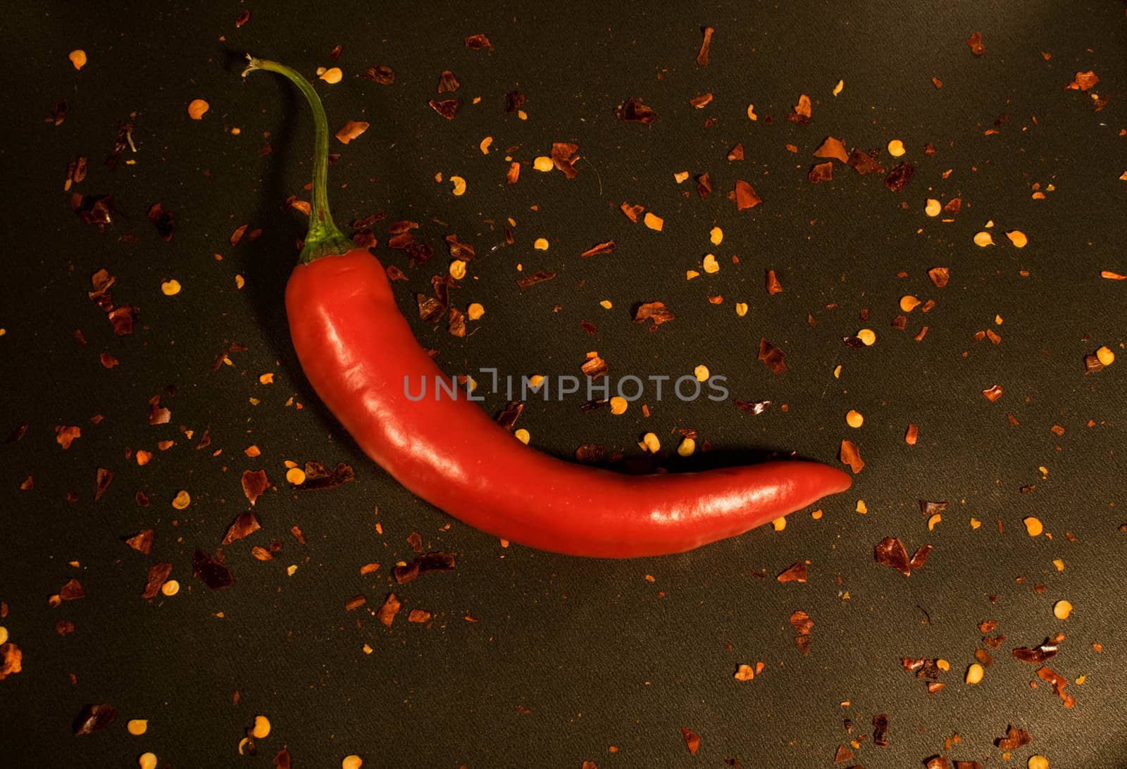 Red hot chili pepper whit seeds all around in a drken background