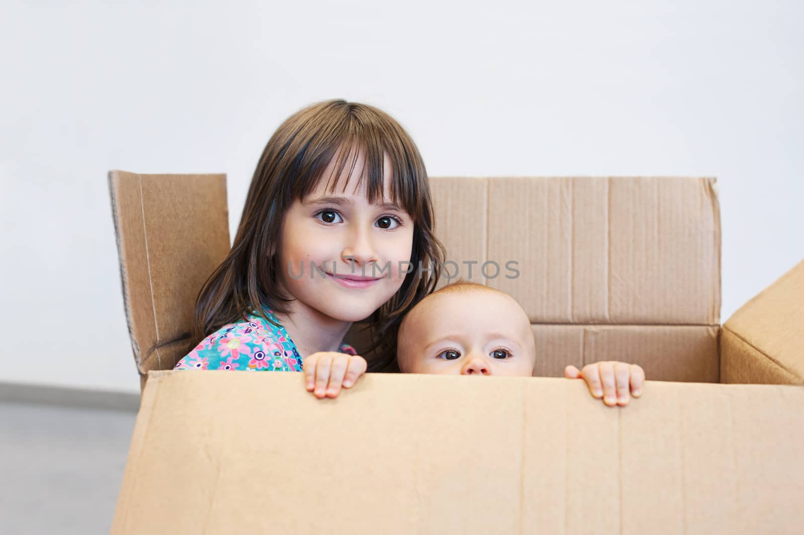 Sisters playing in a carton box  by Olinkau