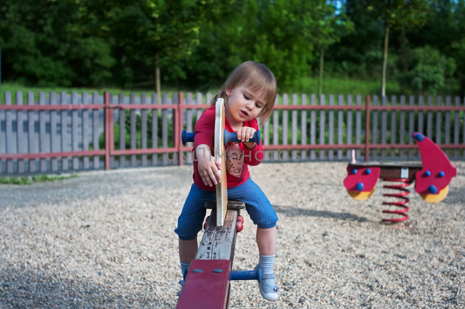Little girl playing on a teeter on the playground