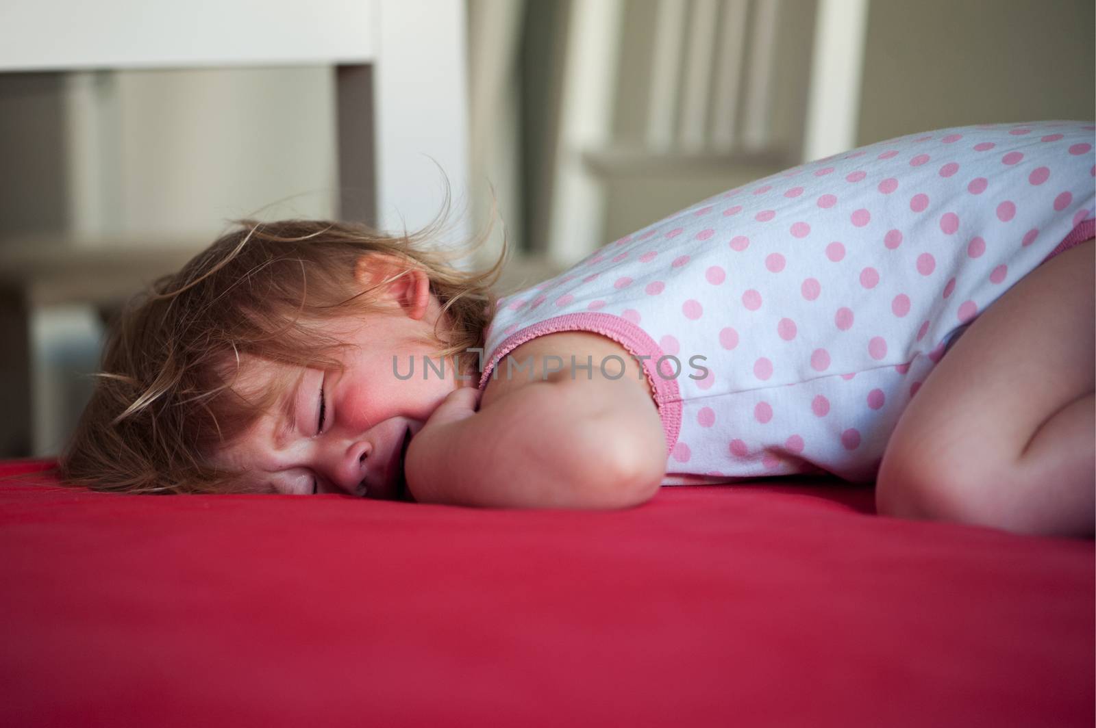 Sick baby girl lying in bed and crying by Olinkau
