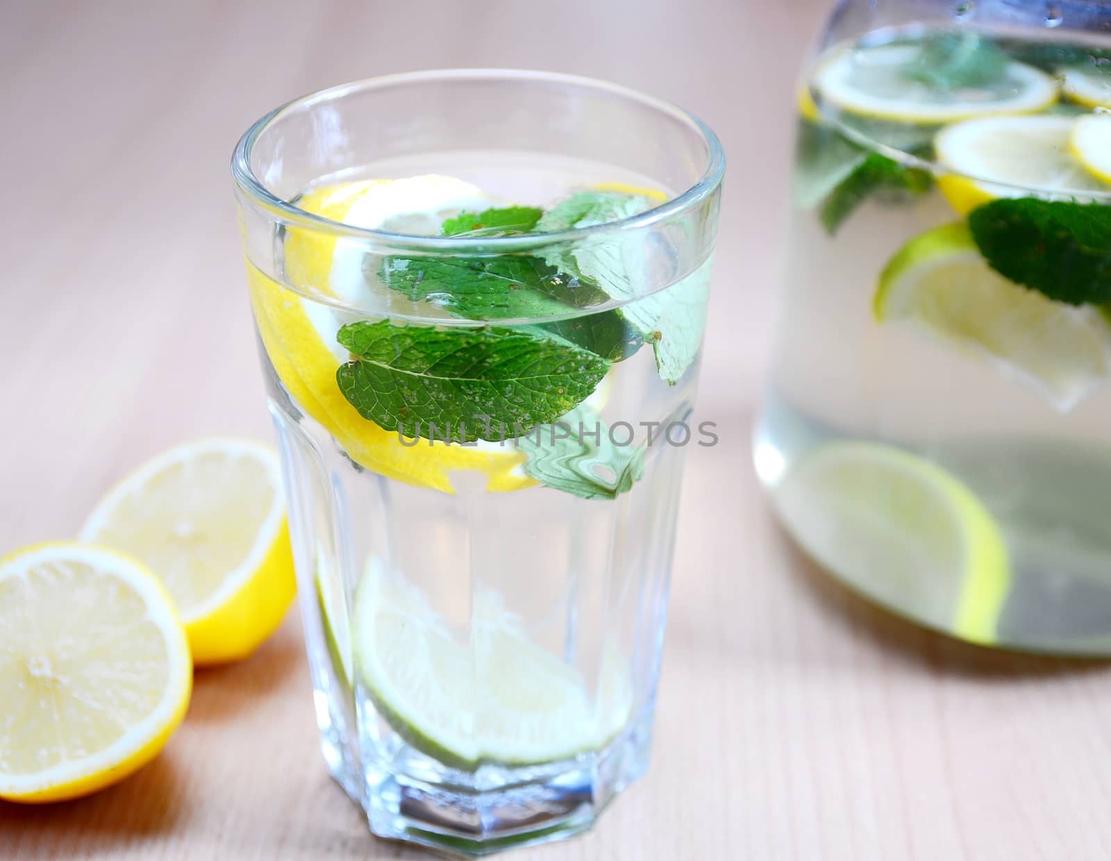 Fresh non-alcoholic drink with water, mint leaves, peaces of lemons and limes in glass.