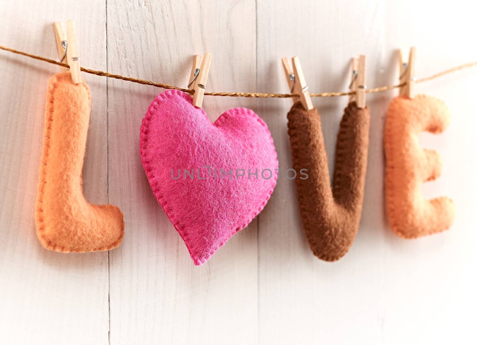 Love, Valentines Day. Word Love, Heart Handmade, hanging on rope. Vintage romantic style, white wooden background, toned. Vivid unusual creative greeting card, multicolored felt