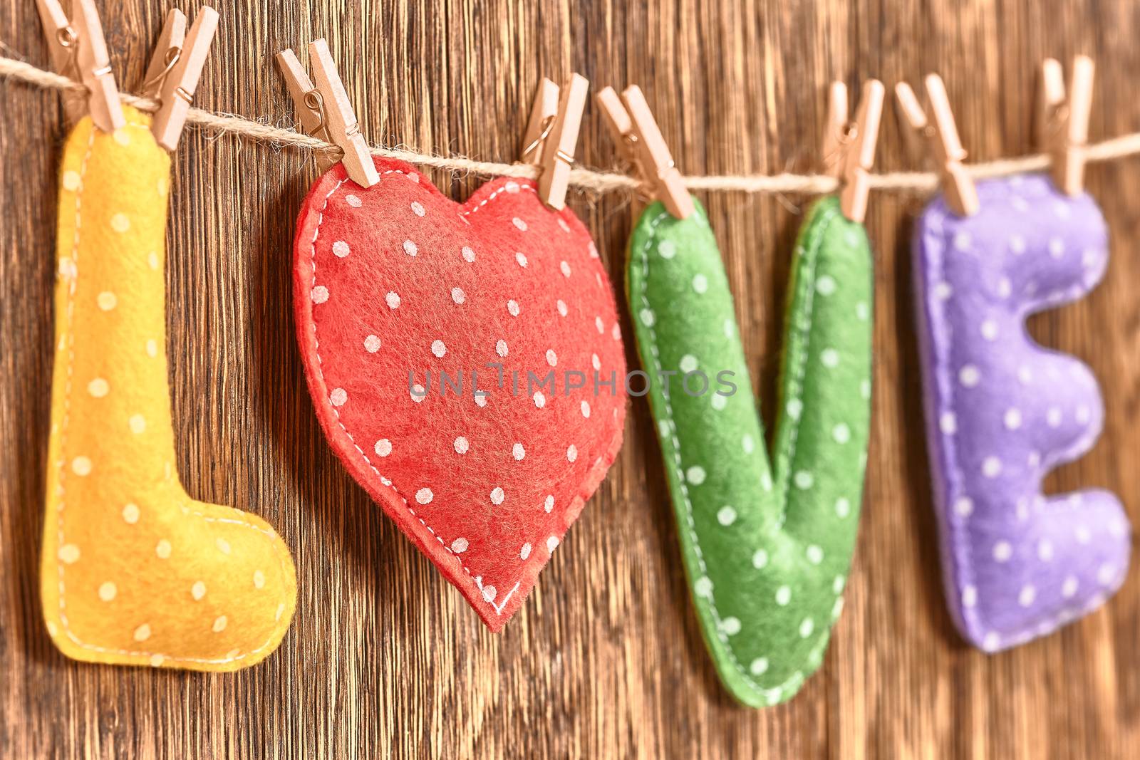 Love, Valentines Day. Word Love polka dots, Heart Handmade, hanging on rope. Retro vintage romantic style, wooden background, toned. Vivid unusual creative greeting card, multicolored felt