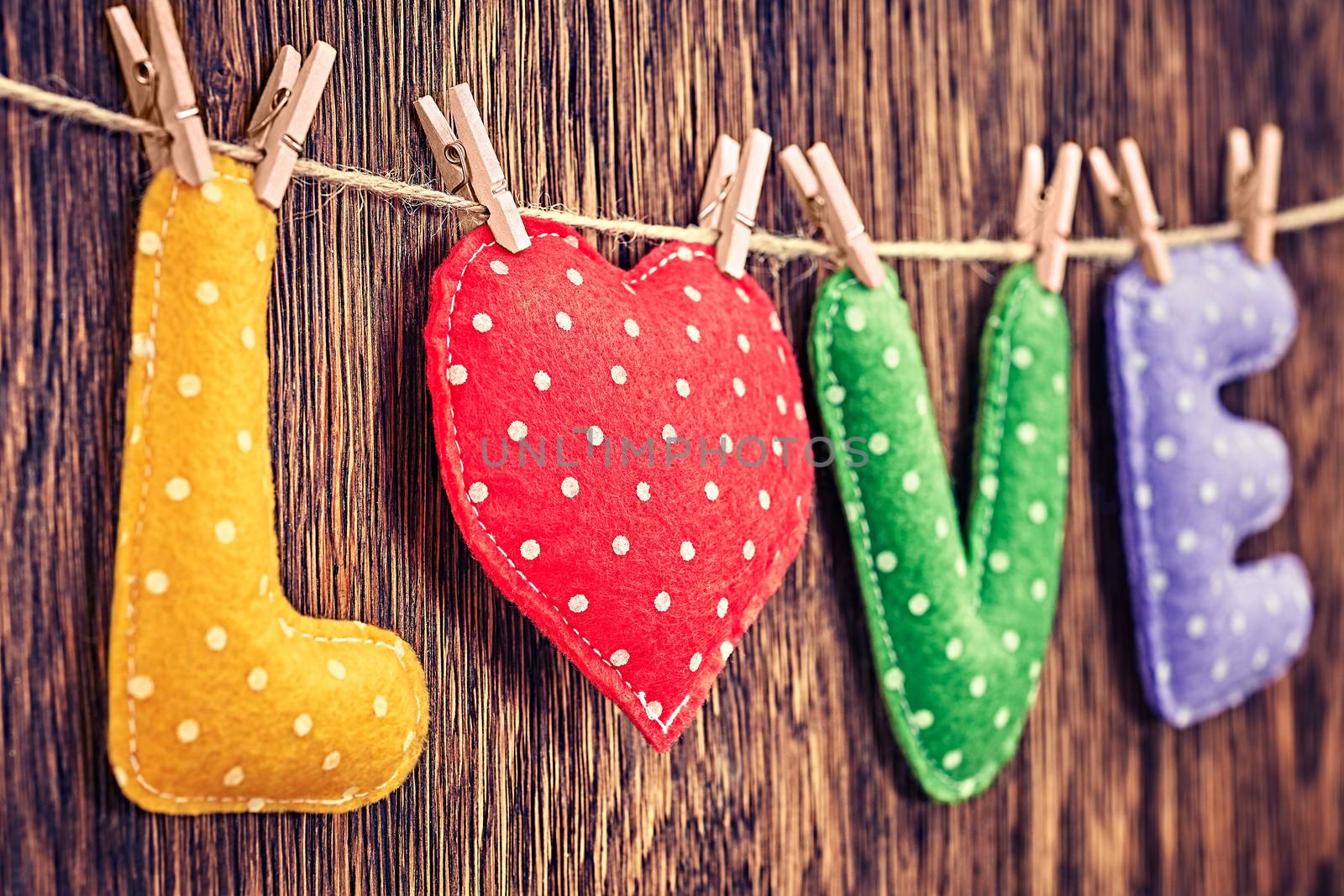 Word Love polka dots, Heart Handmade, hanging on rope. Valentines  Day. Retro vintage romantic style, wooden background, toned. Vivid unusual creative greeting card, multicolored felt