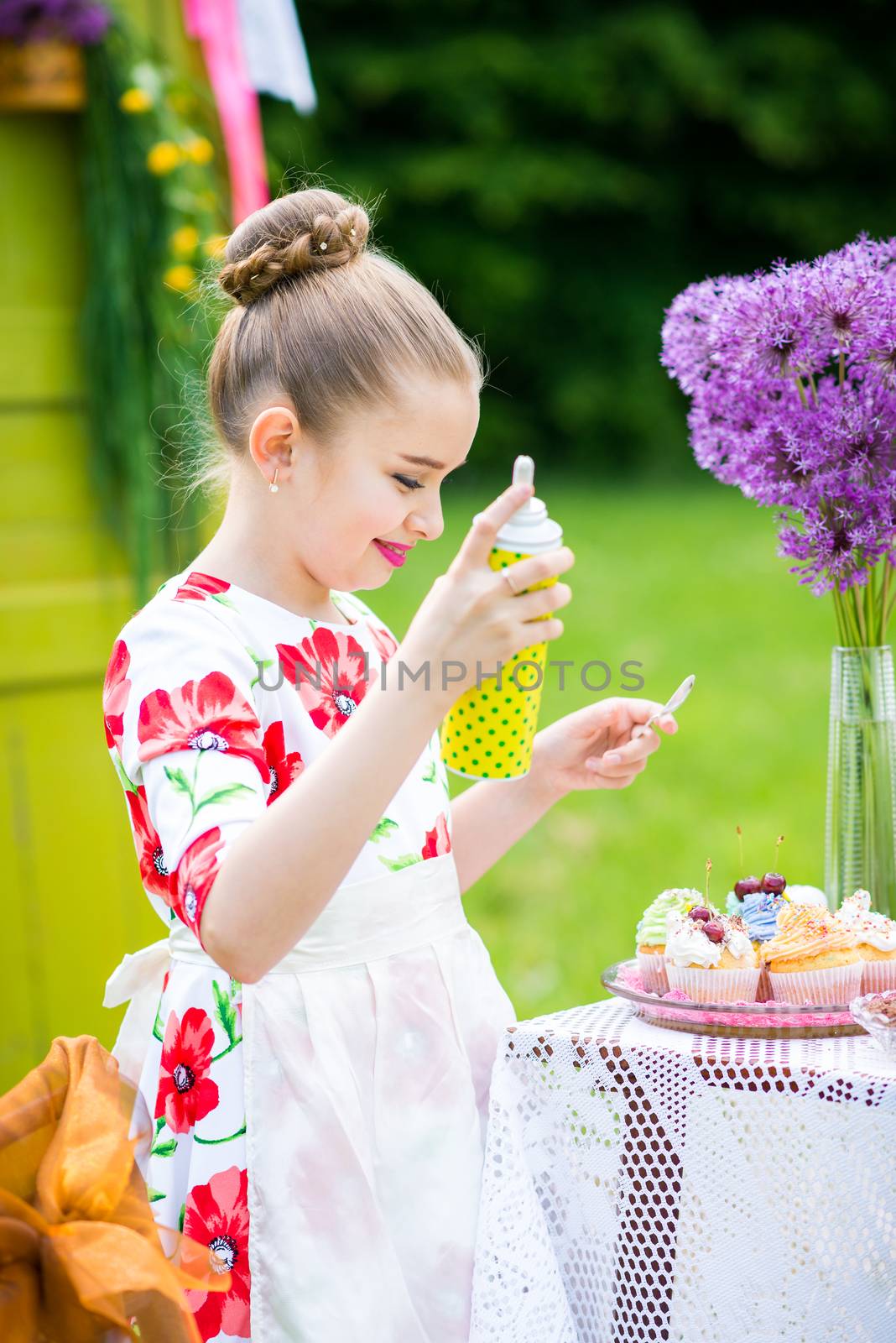 Little girl decorating cupcakes in in the backyard