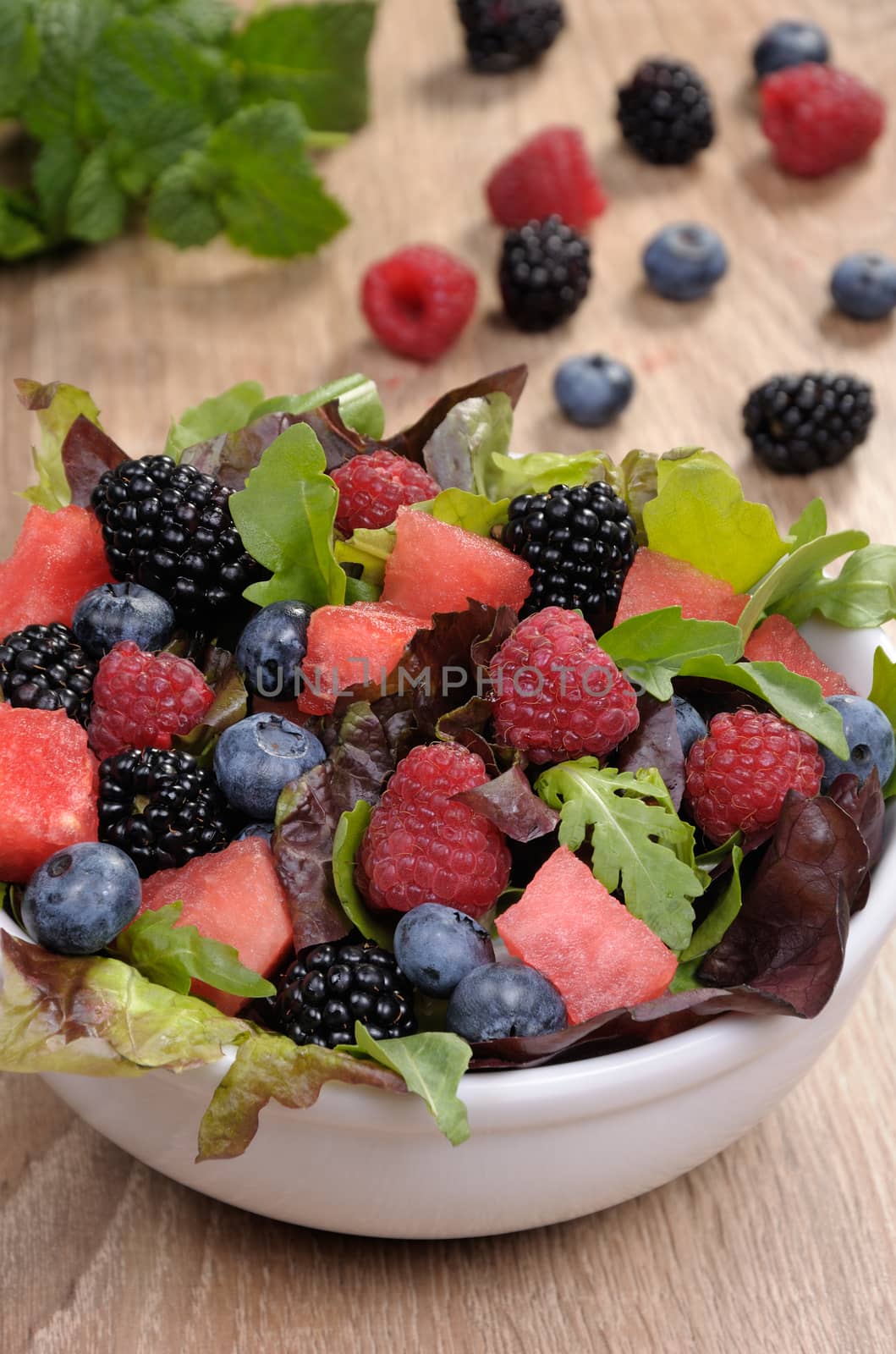 Fruit salad with blackberry, raspberry, blueberry, watermelon slices and mix of green leaves