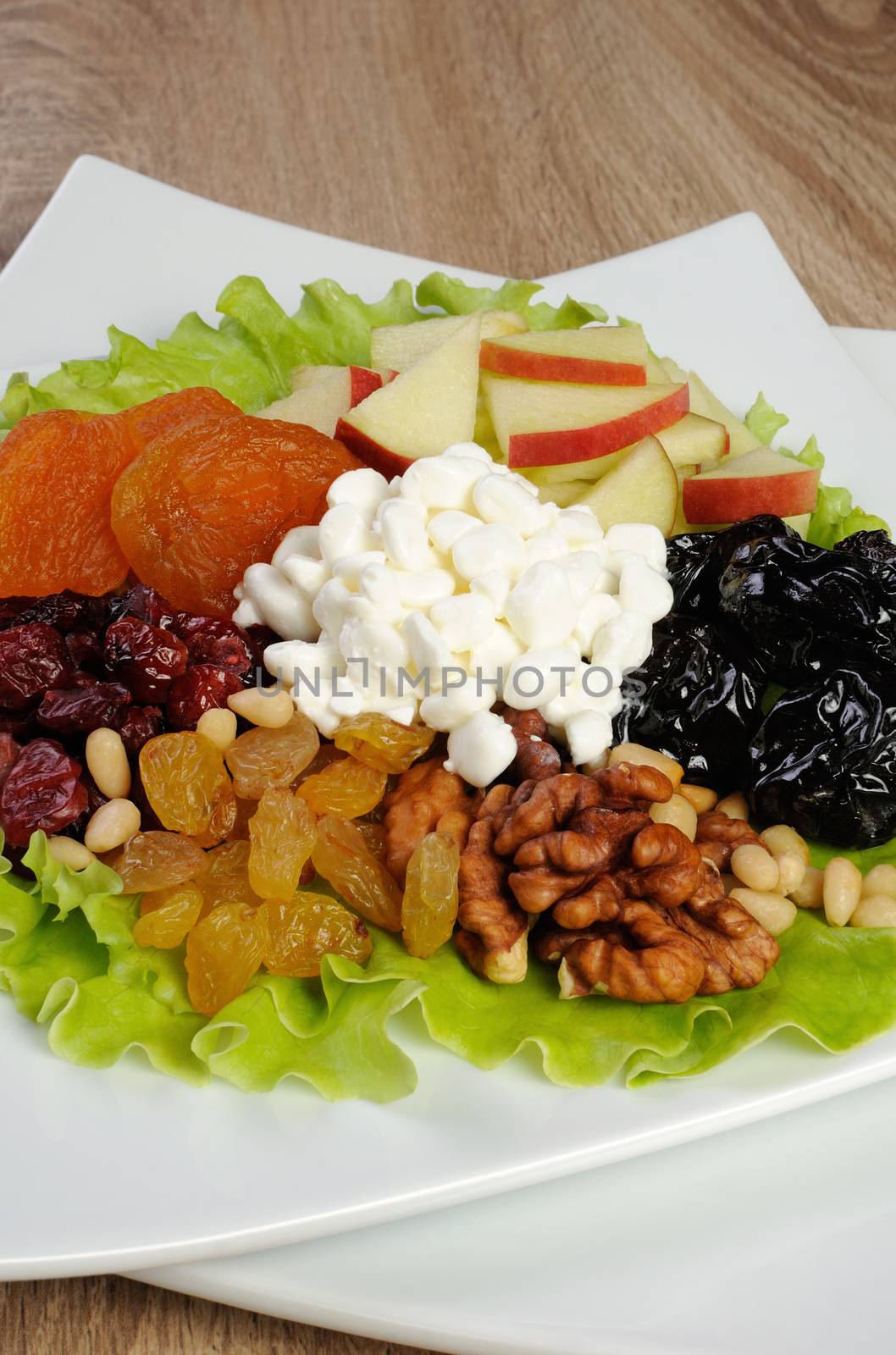 Vitamin salad with nuts, apples, dried fruit and cottage cheese in lettuce leaves