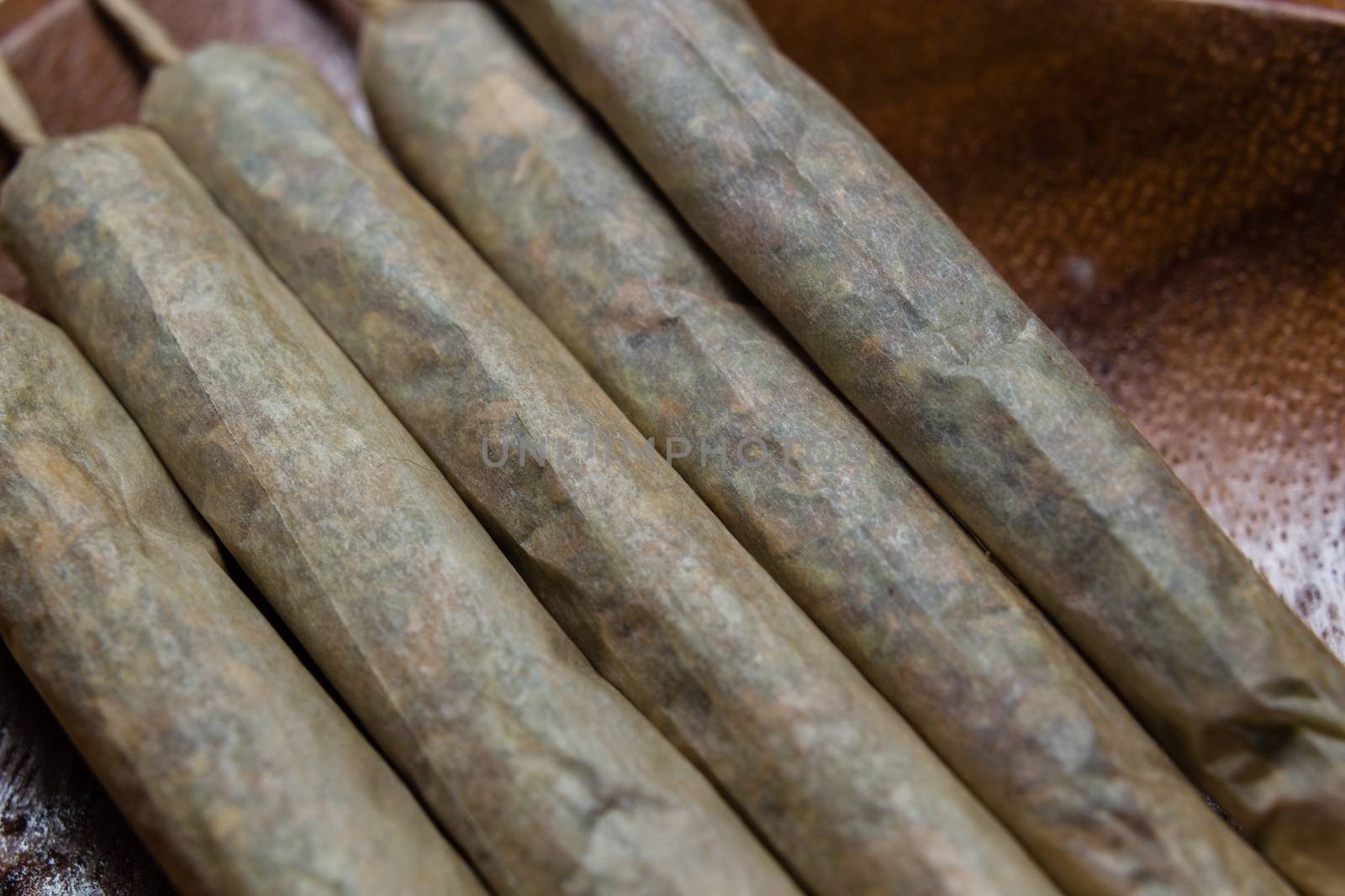 stock of hand made marijuana joints on wooden platter by johnqsbf