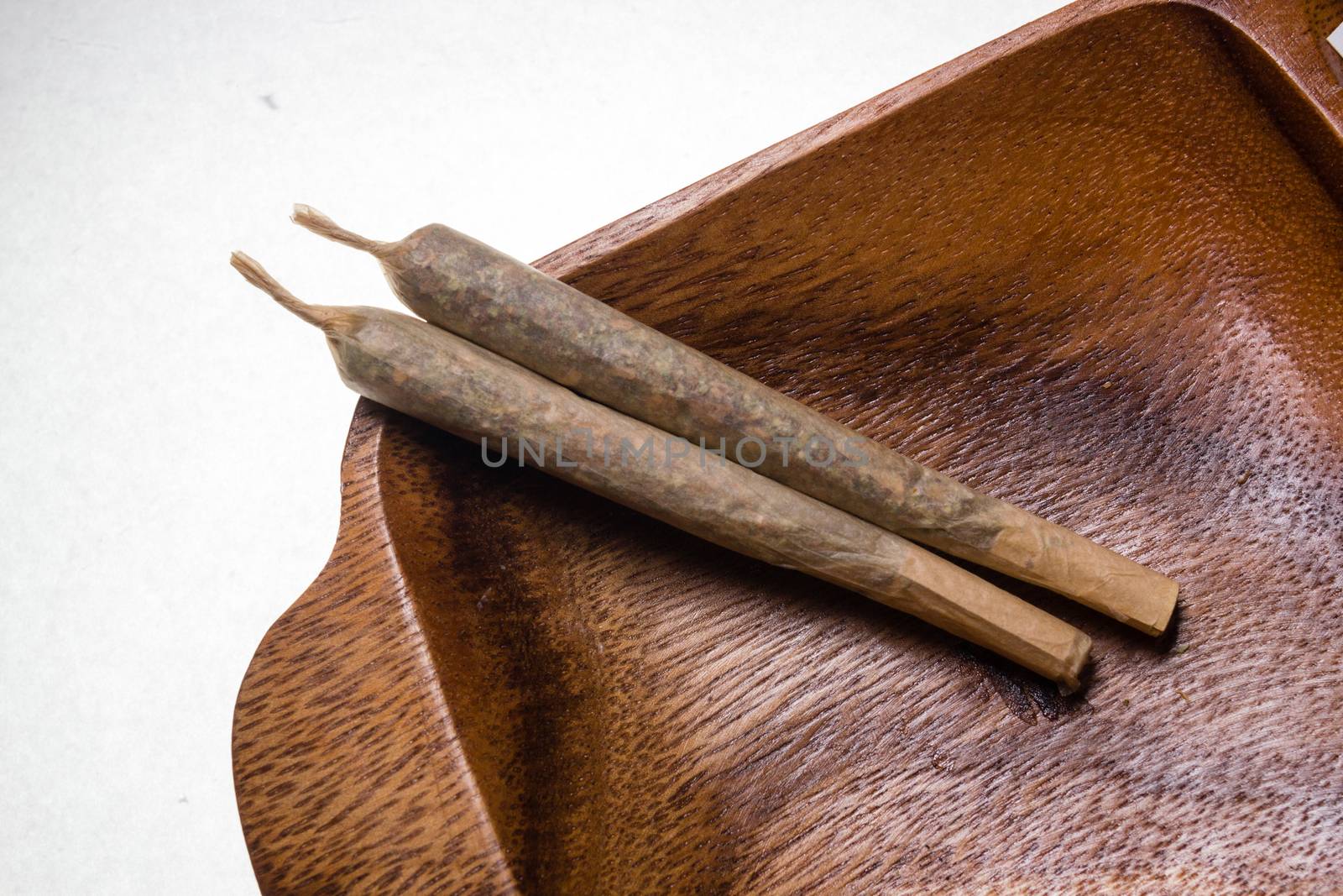 stock of hand made marijuana joints on wooden platter ashtray