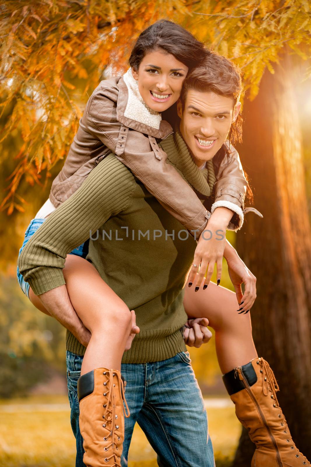 Beautiful young couple having fun in the park in autumn.