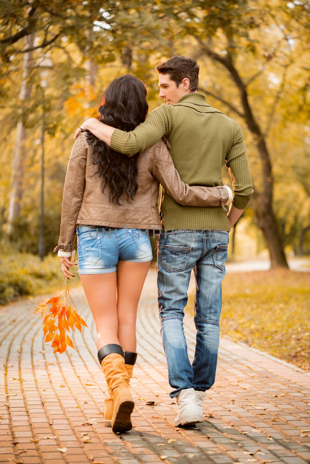 Loving young couple walking and enjoying autumn day in the park.
