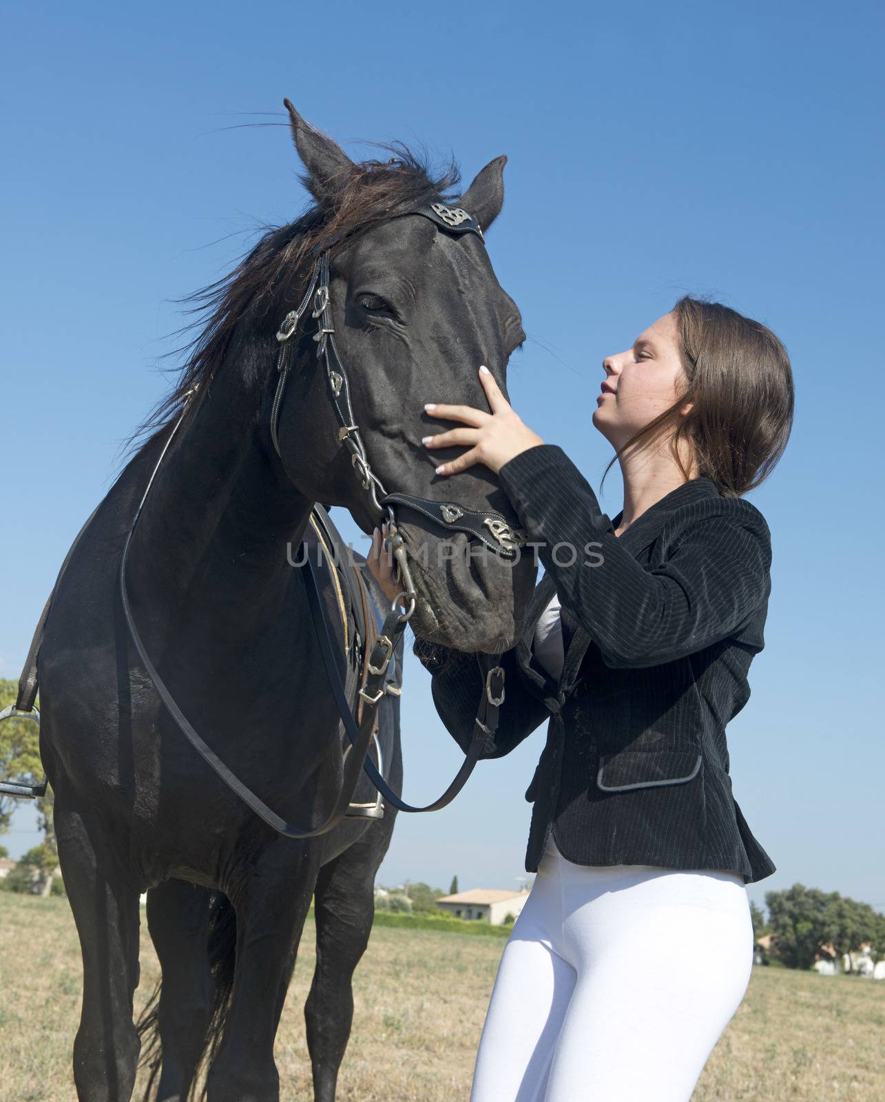 young girl riding a black stallion in a field