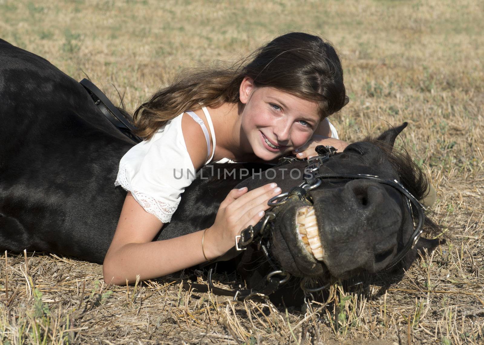 young girl riding a black stallion in a field
