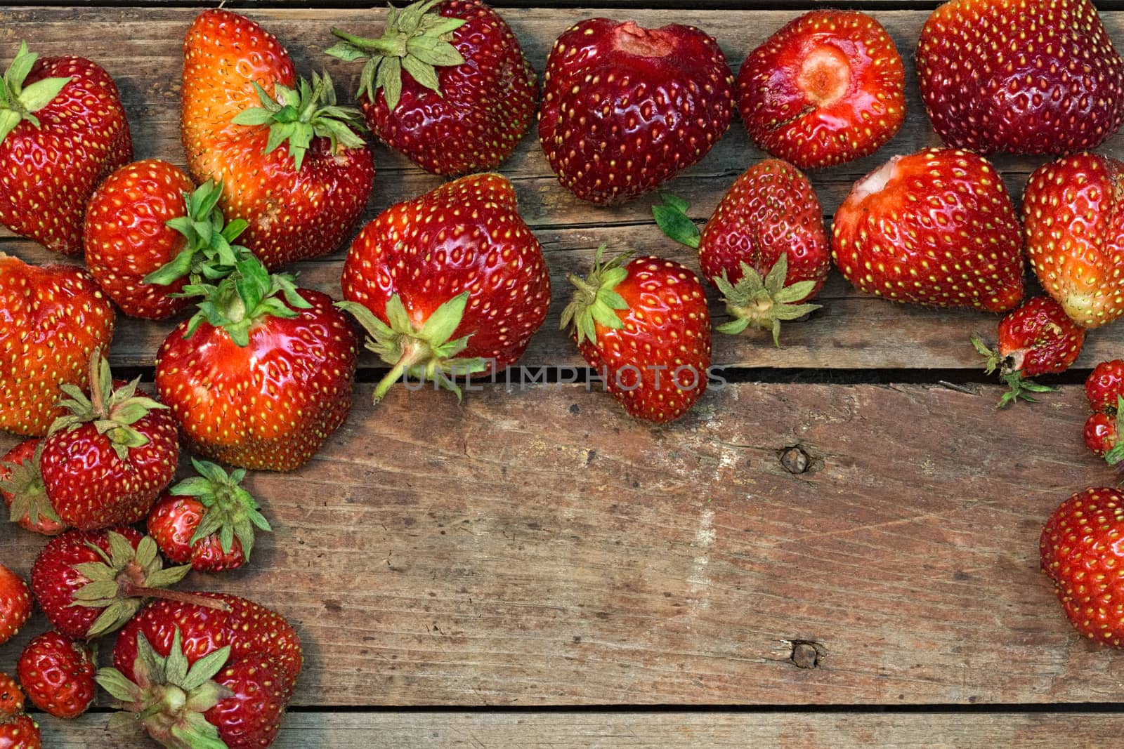 Several ripe red strawberries on a rough wooden background. View from above. Close-up image with copy-space